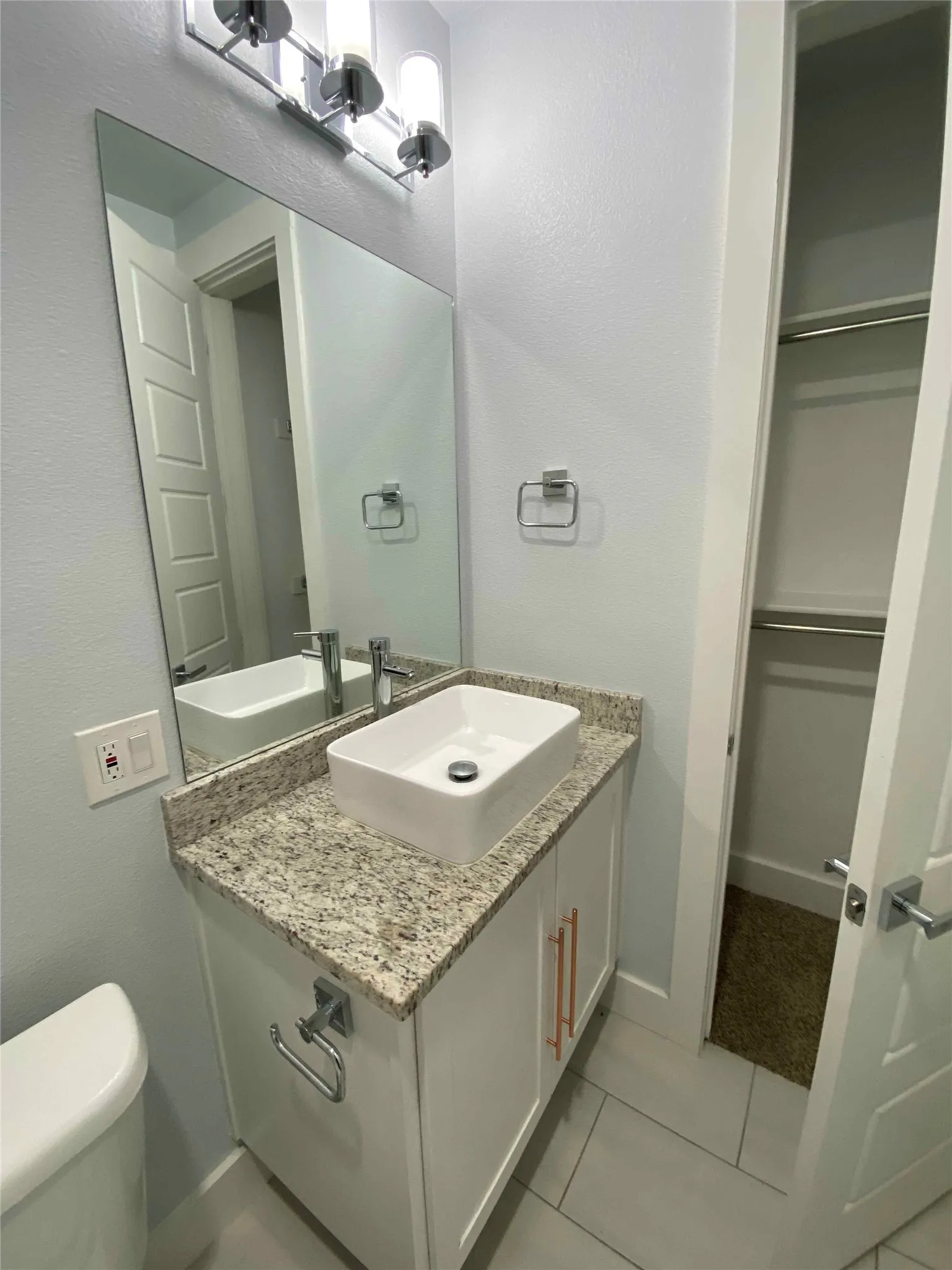 Half bath featuring vanity, light tile patterned floors, and a textured wall
