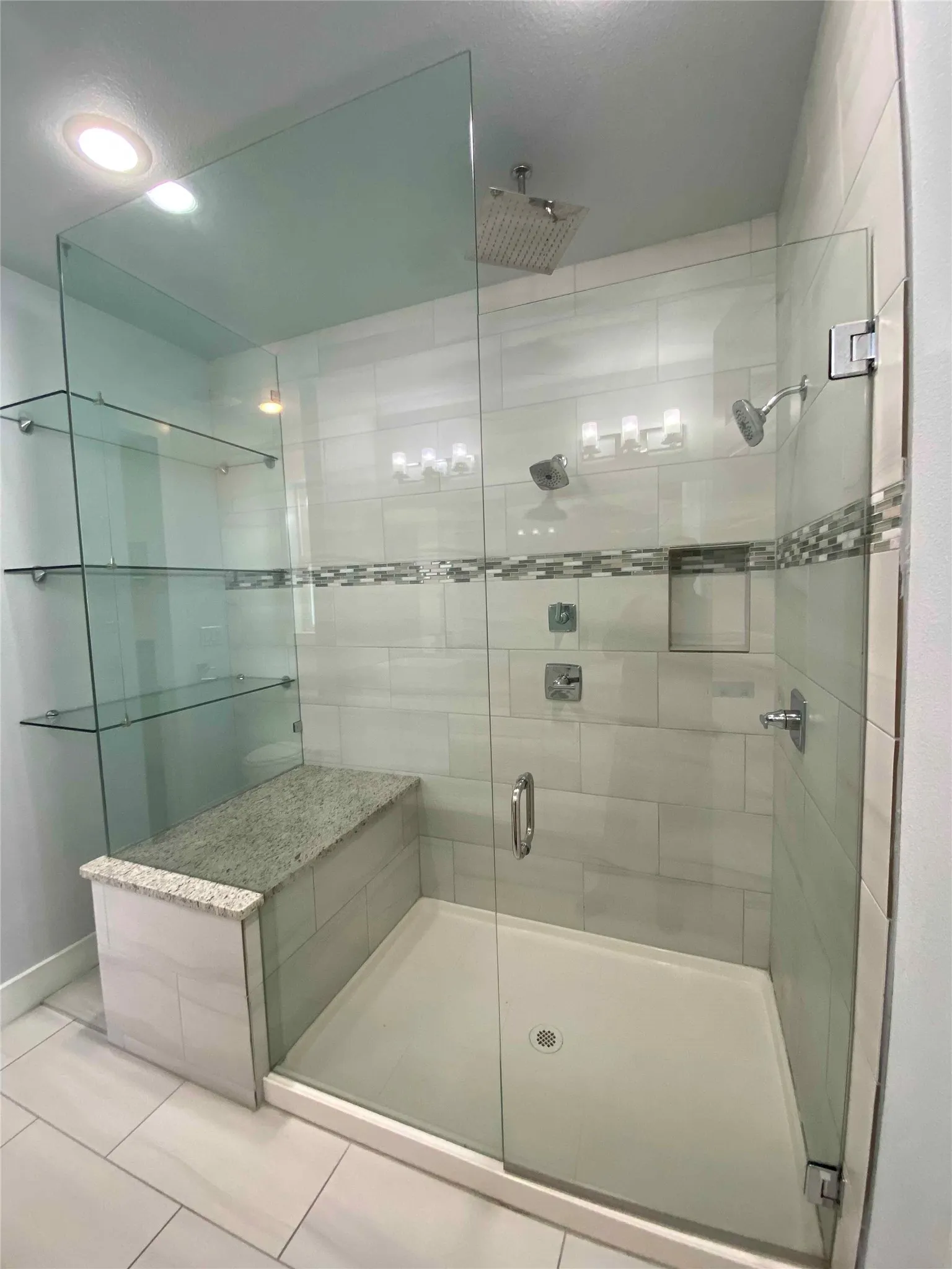 Full bathroom featuring a glass stall shower and tile, patterned flooring and rain shower
