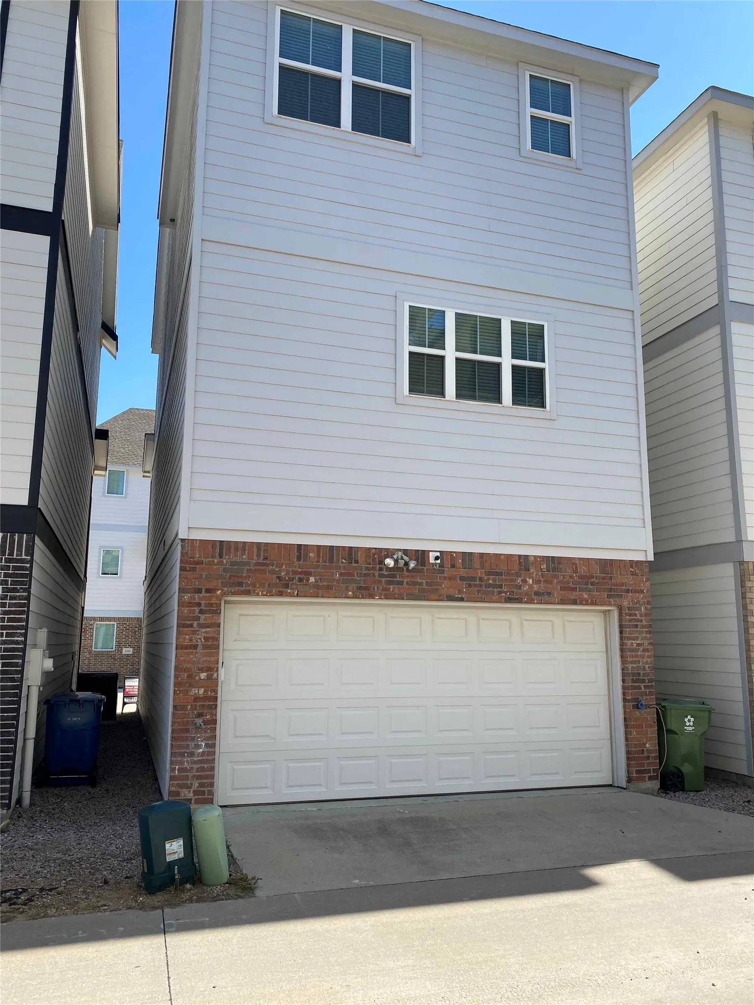 Rear view of house with an attached garage, security camera and motion detect light