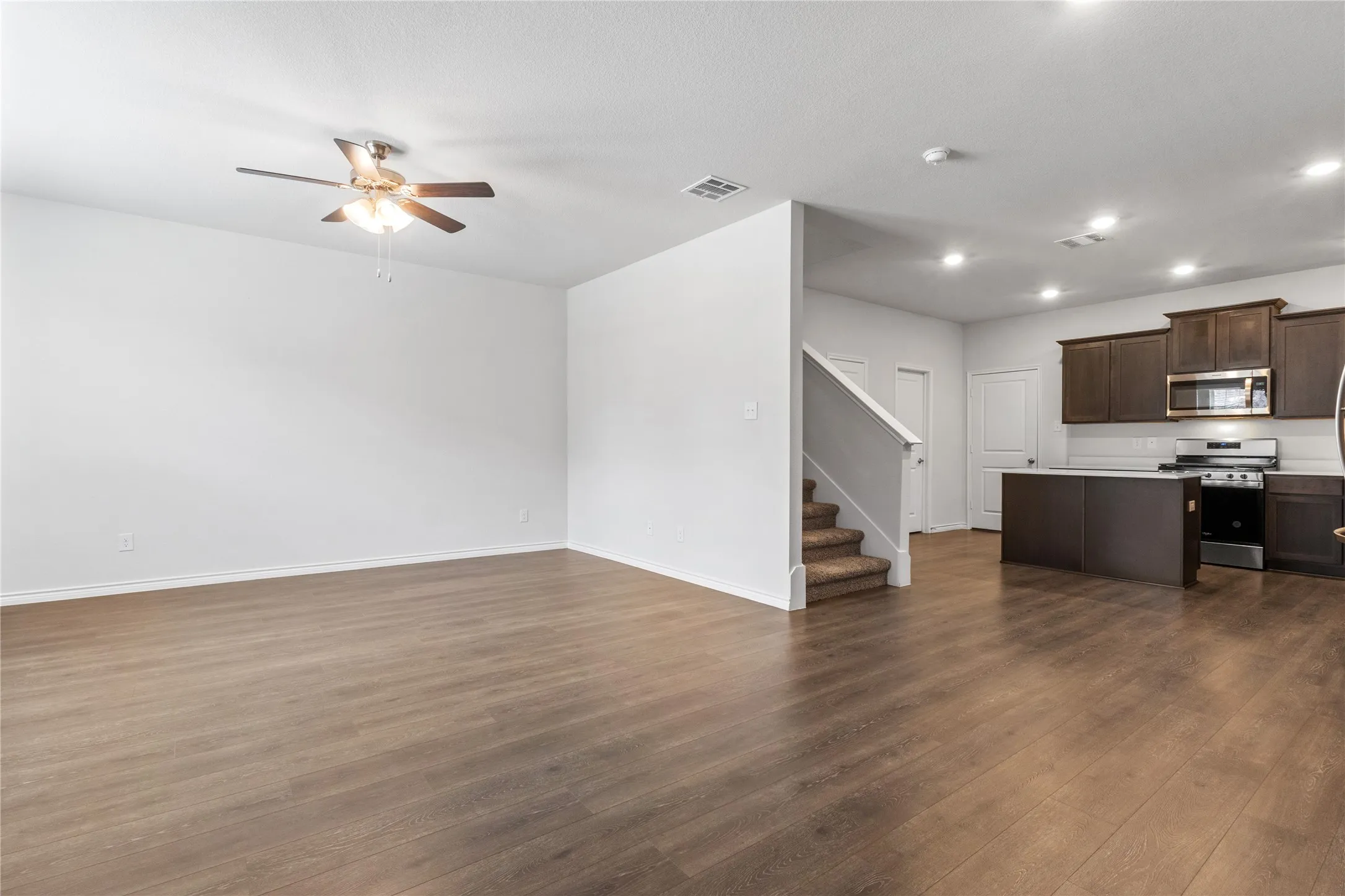 Unfurnished living room with ceiling fan, stairs, dark wood-style flooring, recessed lighting, and baseboards
