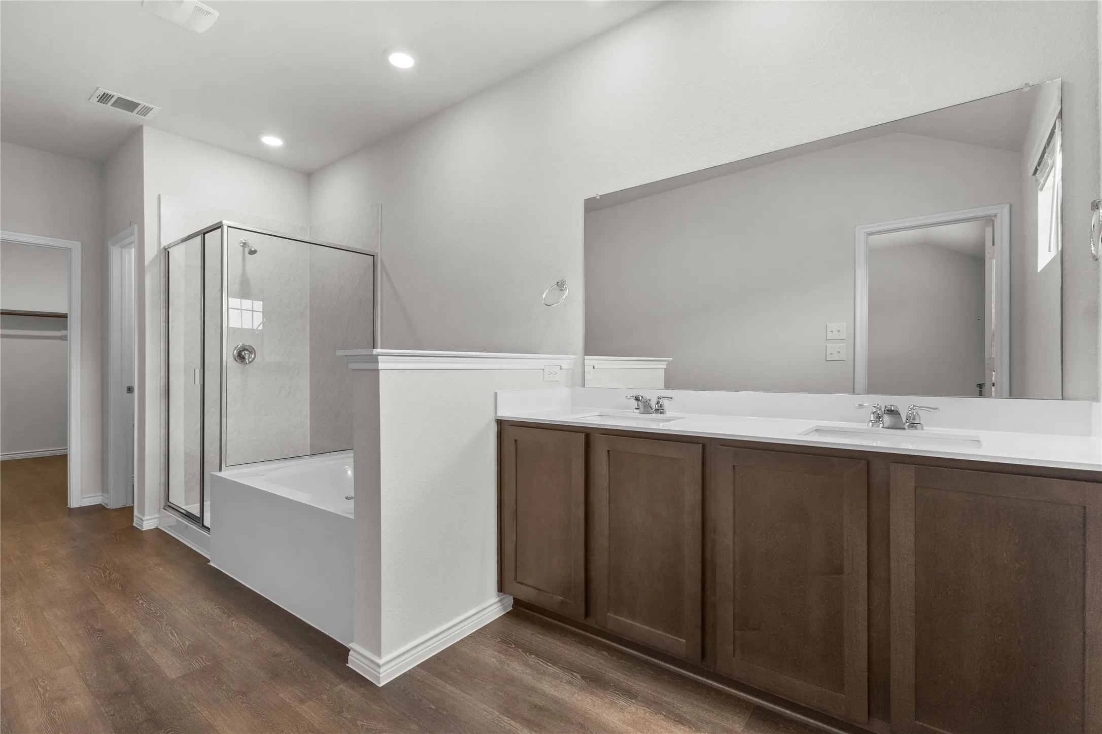Bathroom with a stall shower, wood finished floors, a garden tub, double vanity, and recessed lighting