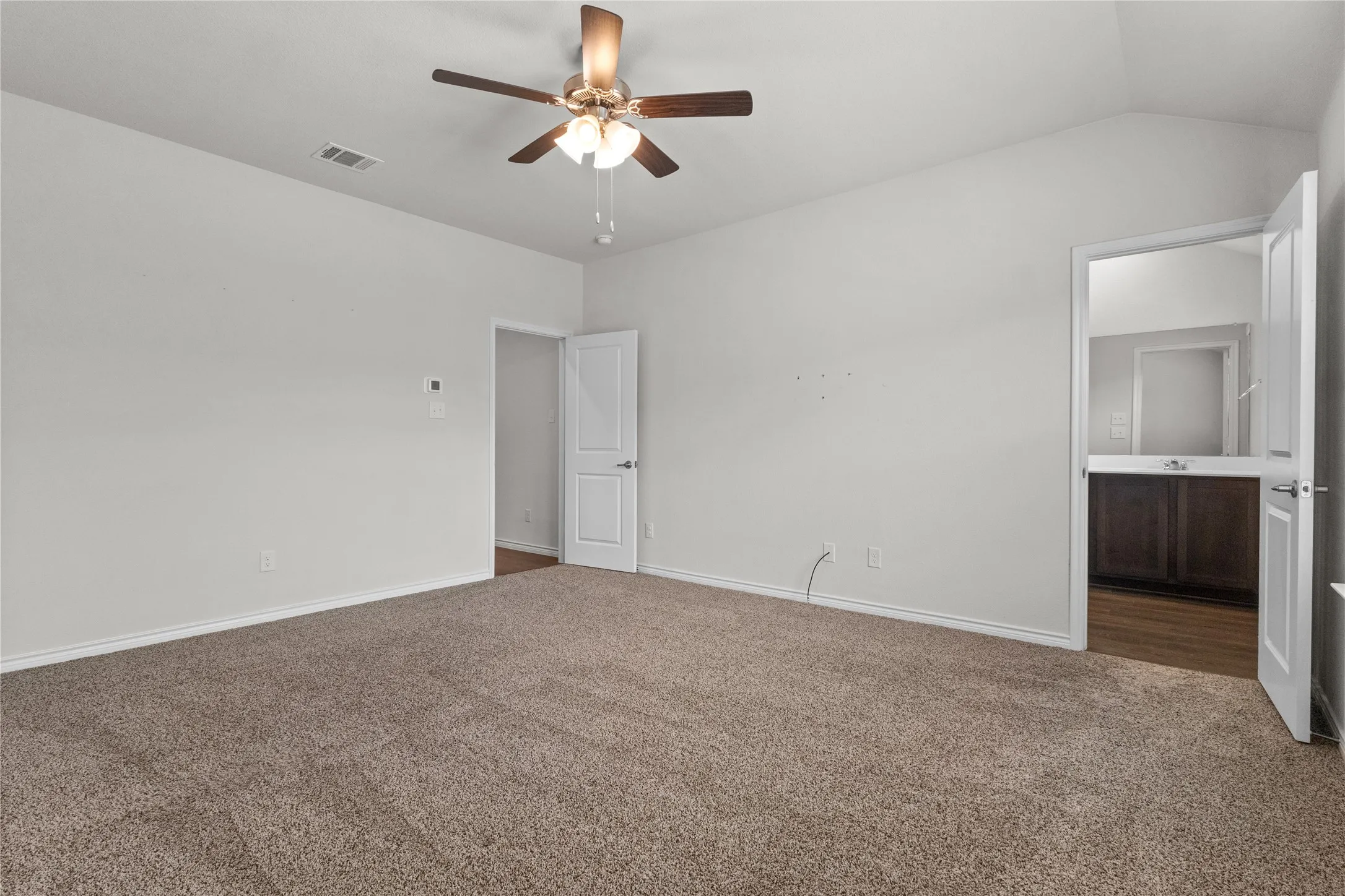 Spare room featuring carpet flooring, ceiling fan, baseboards, and vaulted ceiling