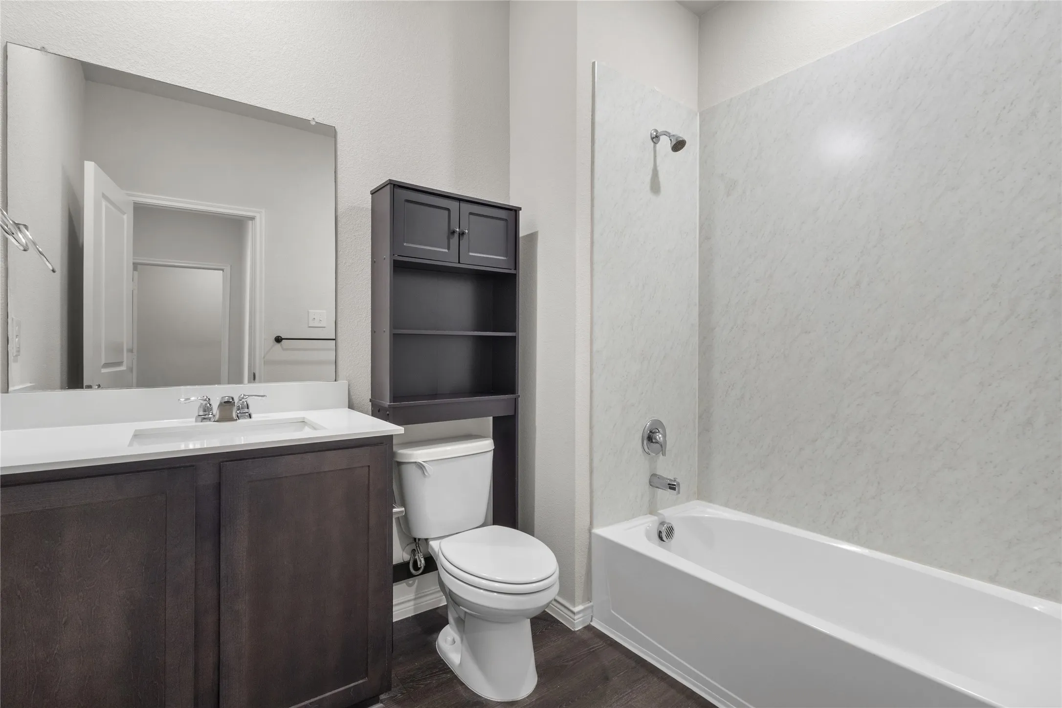 Bathroom featuring wood finished floors, toilet, vanity, and shower / bath combination