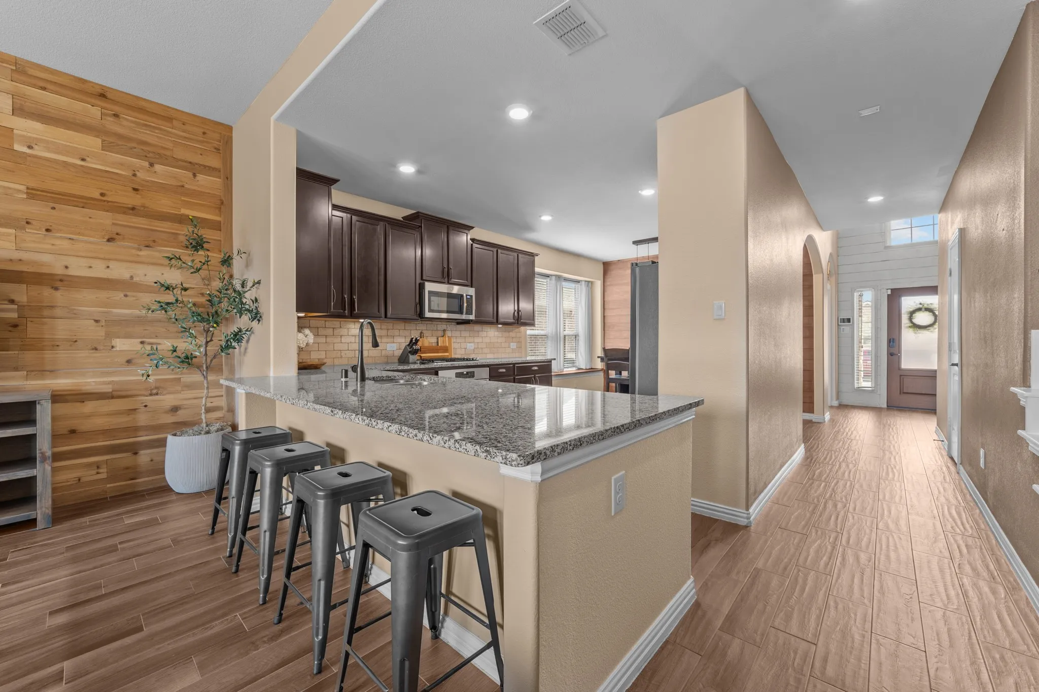Kitchen featuring dark wood cabinetry, granite countertops, and a subway tile backsplash