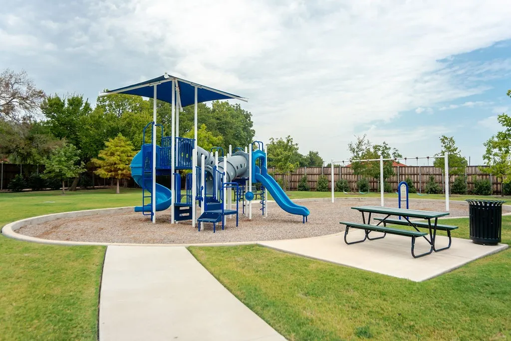 Community playground featuring multiple slides, climbing structures, and a shaded picnic area