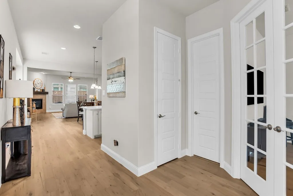 Wood-finish flooring throughout, white interior doors, recessed lighting, double French doors with glass panes, and a fireplace with a wood mantle