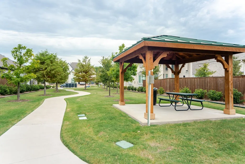 Wood-framed gazebo with a green roof and concrete pad