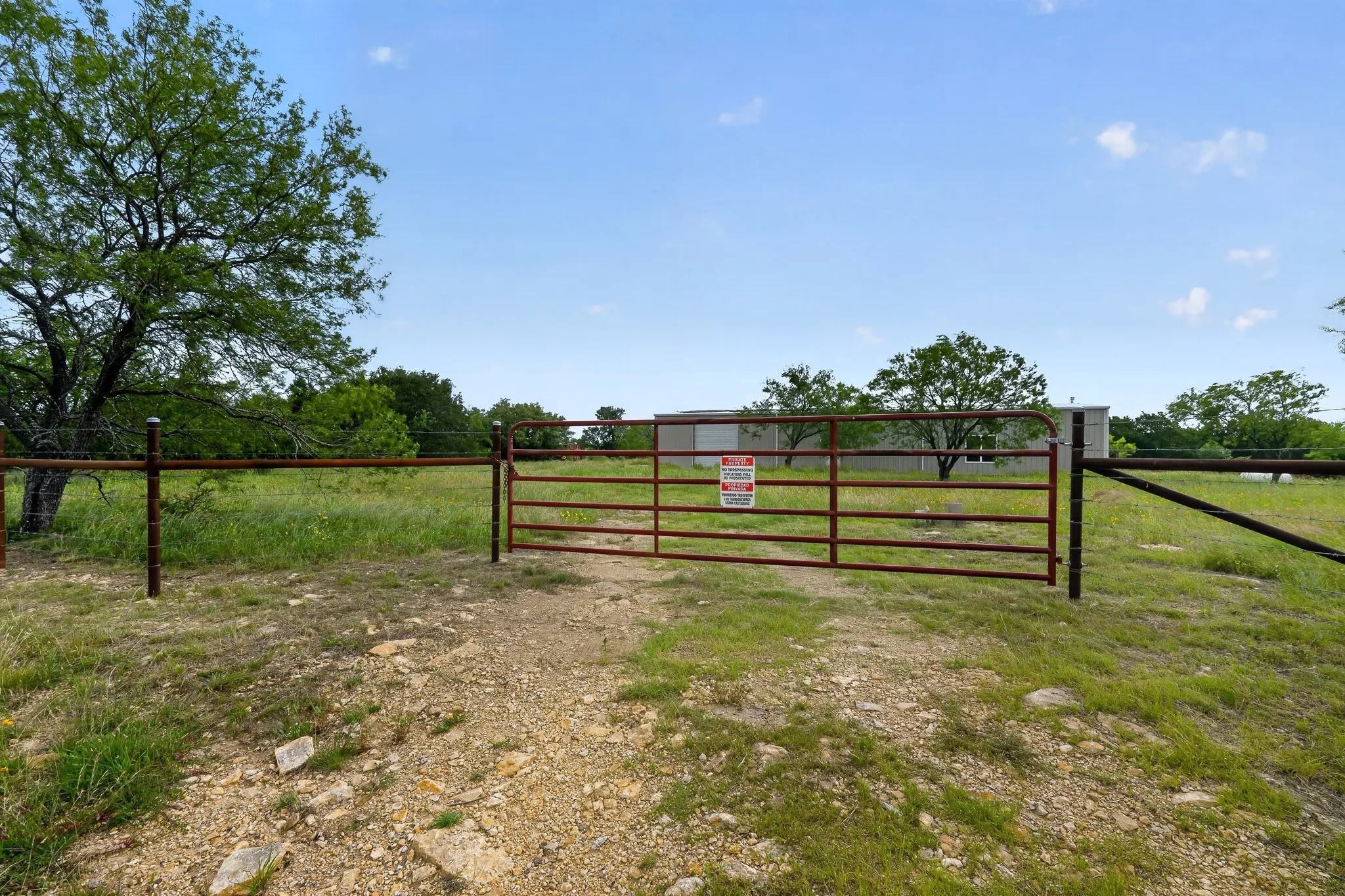 Gated entrance with a metal fence and a gravel path