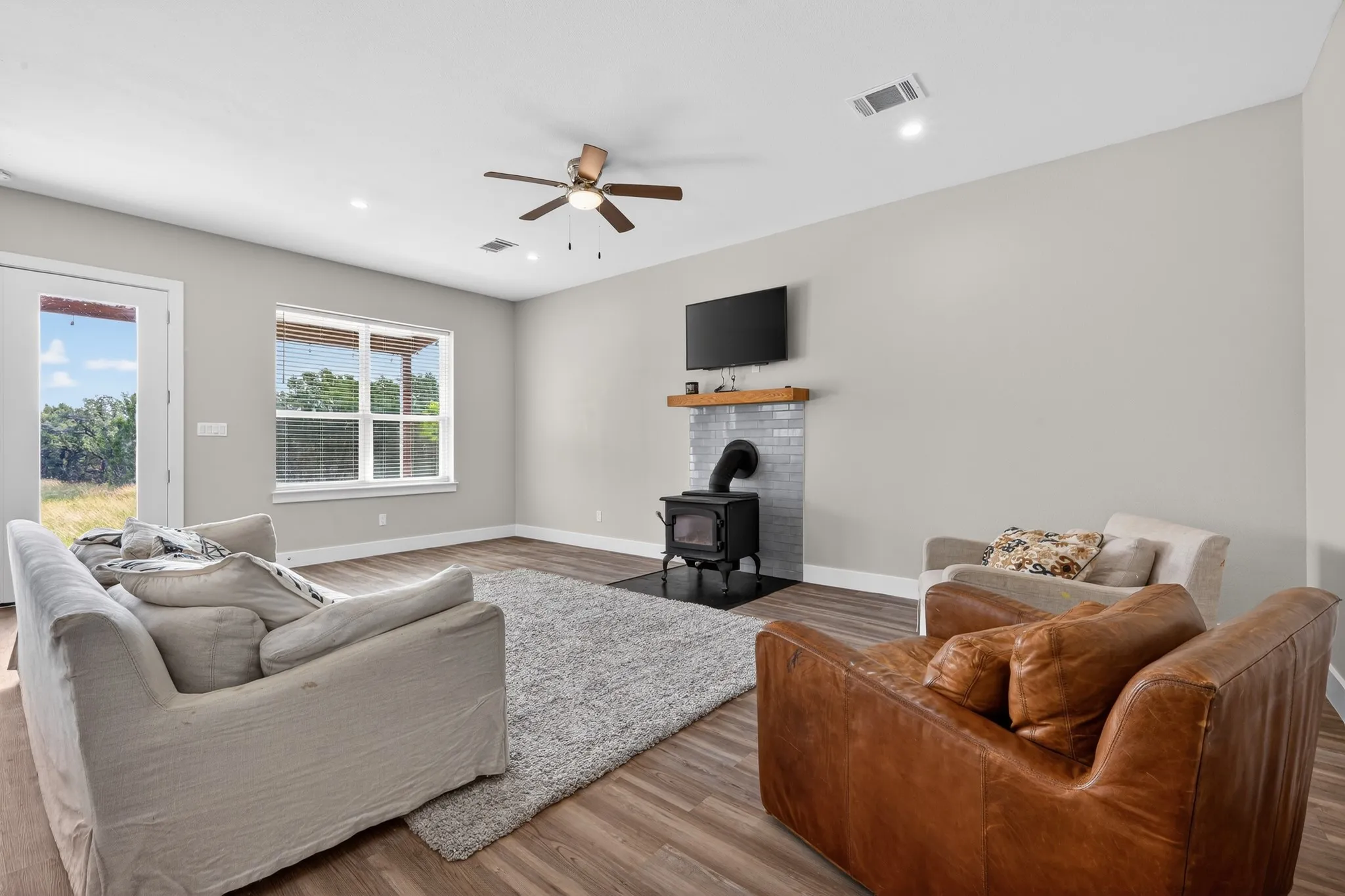 Spacious living area featuring wood-finish flooring, a ceiling fan, recessed lighting, and a window with blinds