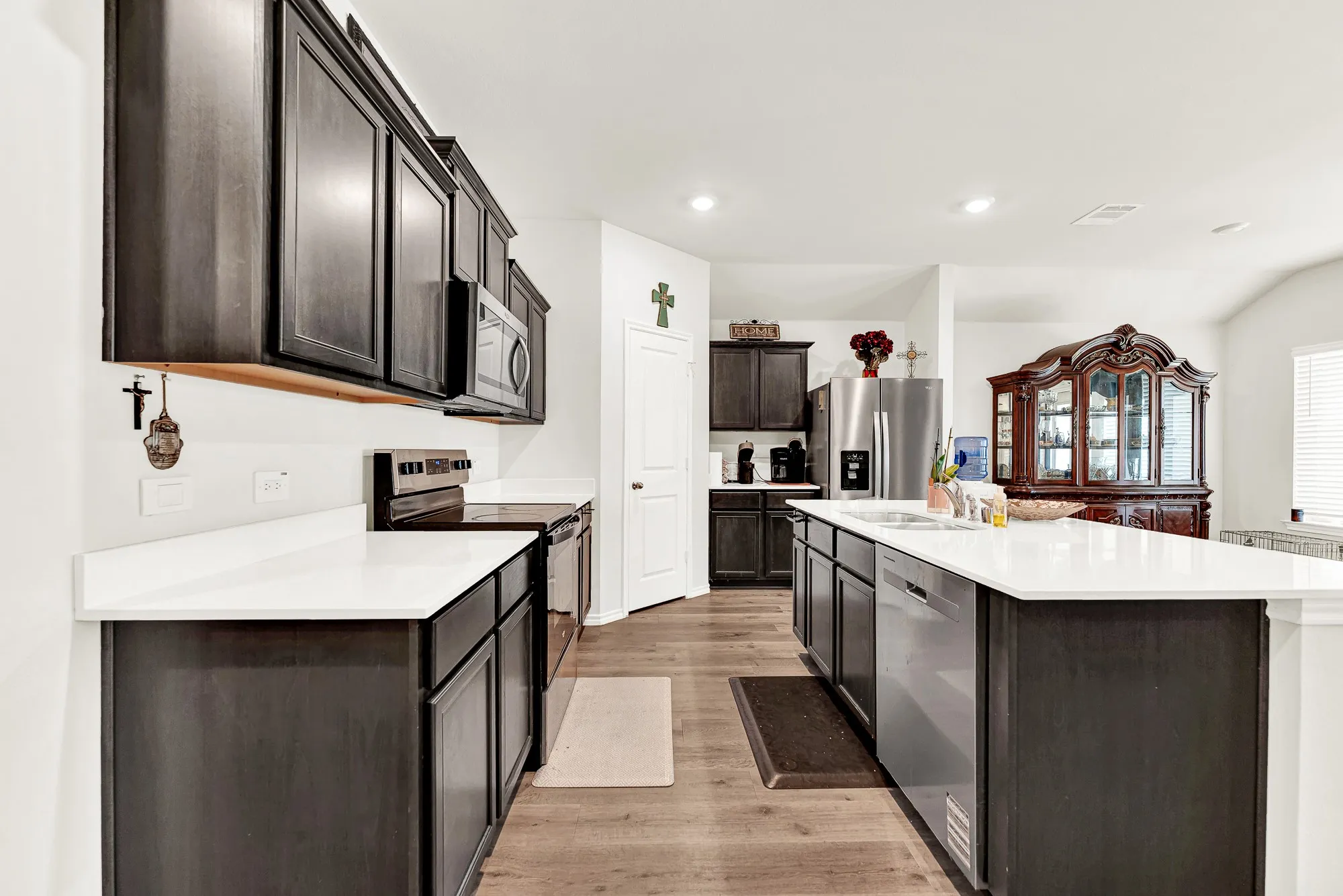 Clean white quartz surfaces provide generous prep space alongside a smooth-top range and an integrated under-mount sink. Preparing dinner feels effortless here with everything organized and right at your fingertips.
