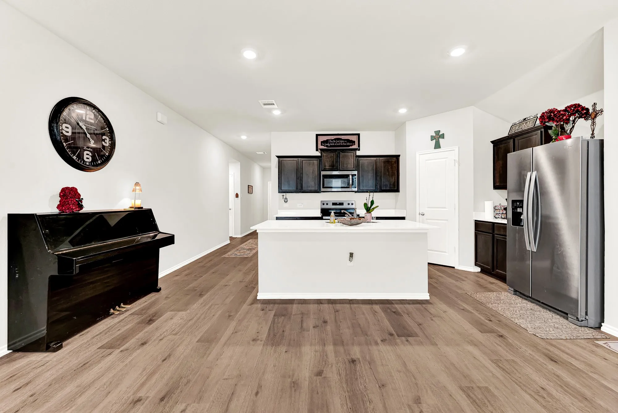 Recessed lighting brightens the open layout, highlighting the contrasting island and matching dark cabinets framing the main cooking area. You will love gathering around the island for quick breakfasts or setting out appetizers when friends drop by.