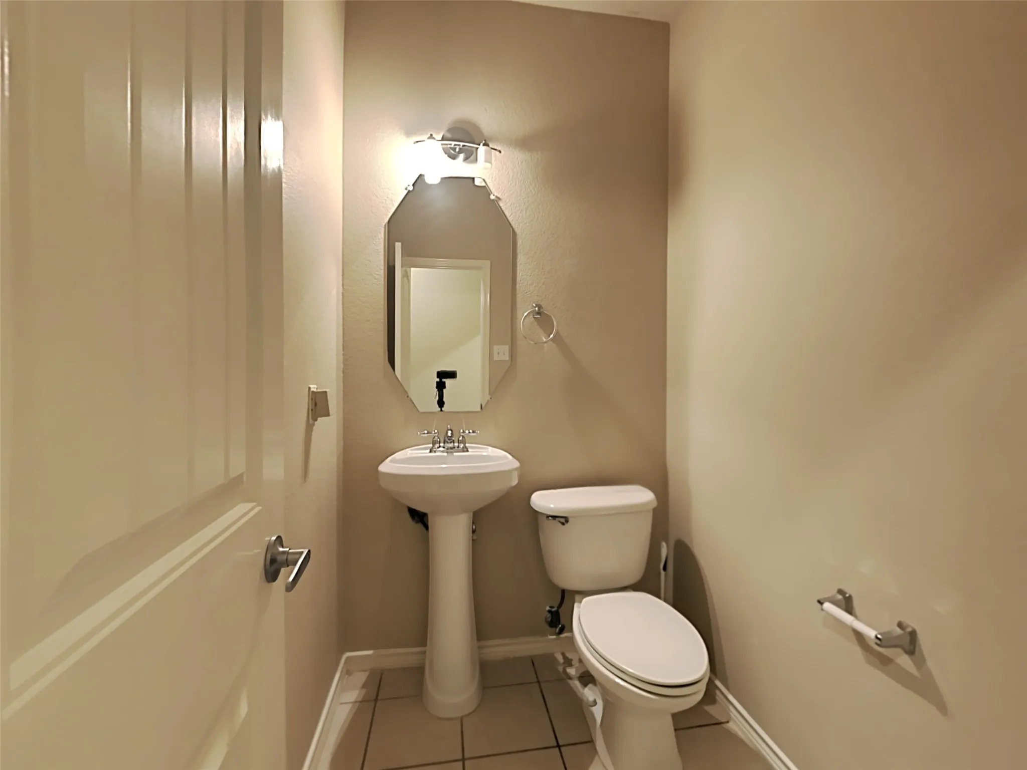 Pedestal sink with an octagonal mirror and wall-mounted light fixture