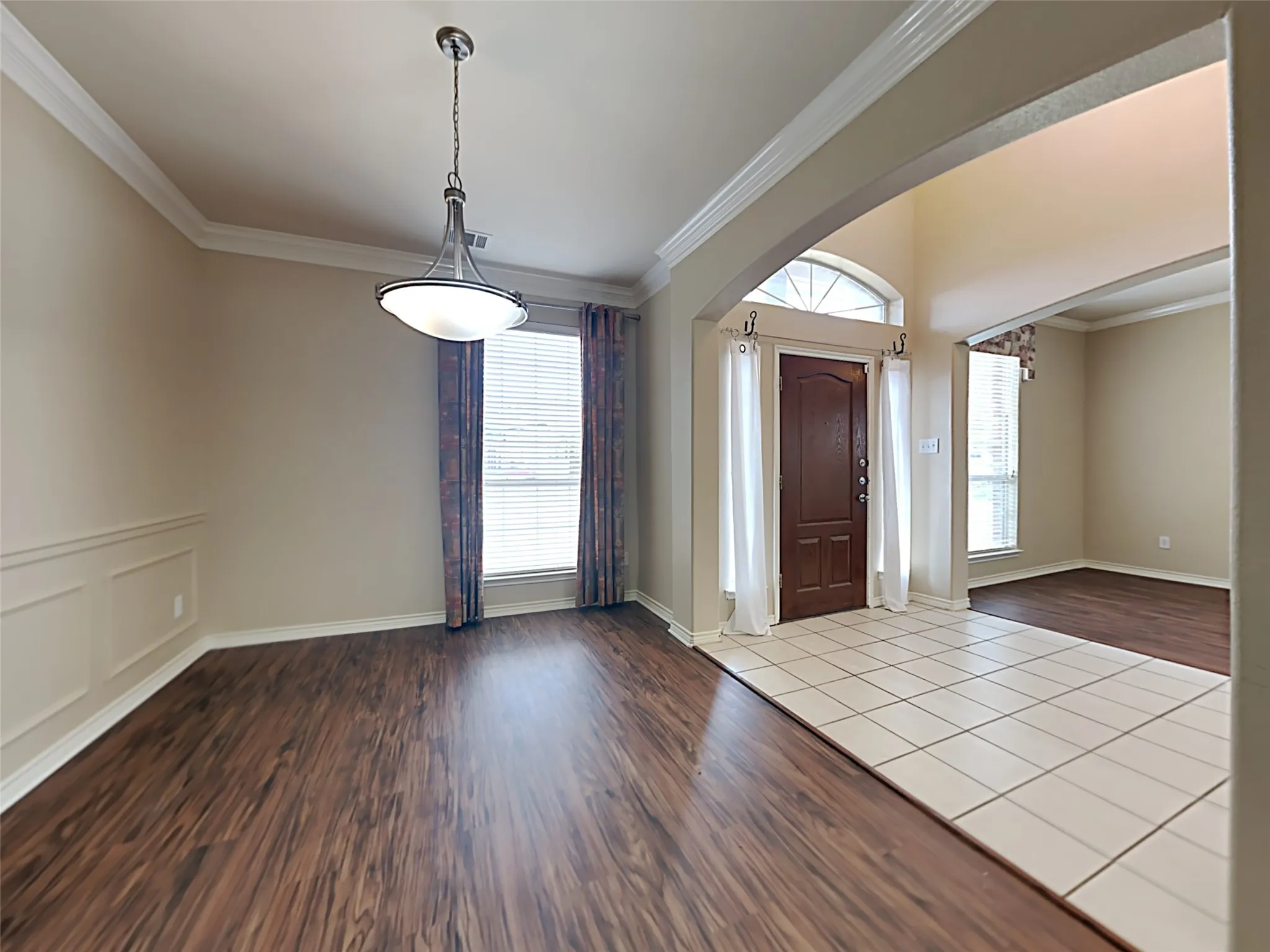 Wood-finish flooring, wainscoting, crown molding, and a decorative pendant light