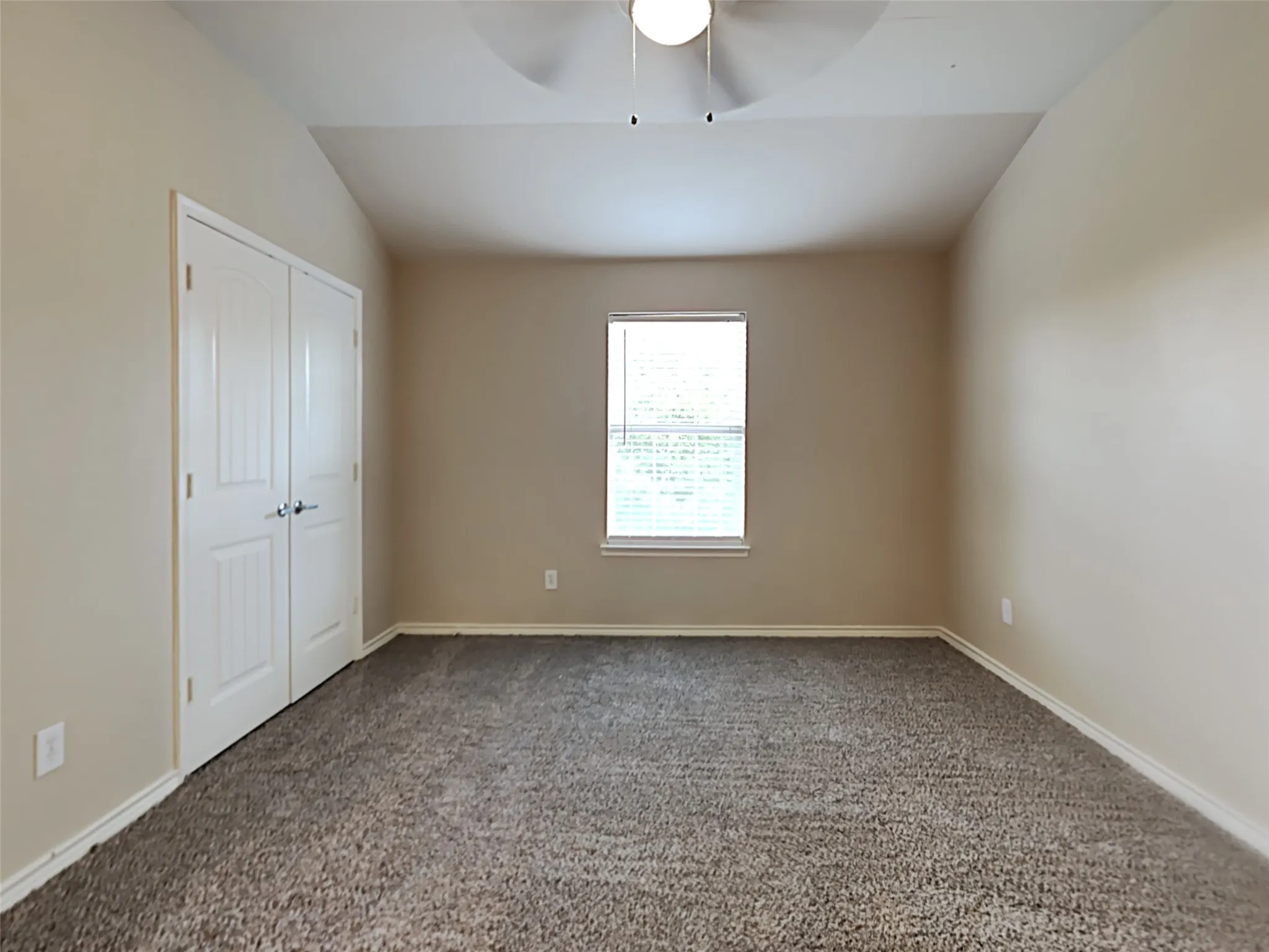Vaulted ceiling with a ceiling fan, neutral wall paint, window with blinds, and double-door closet