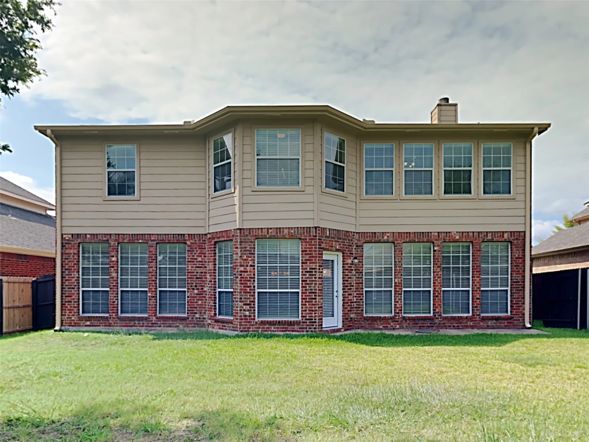 Two-story exterior with brick and siding facade, multiple large windows, and a rear entry door