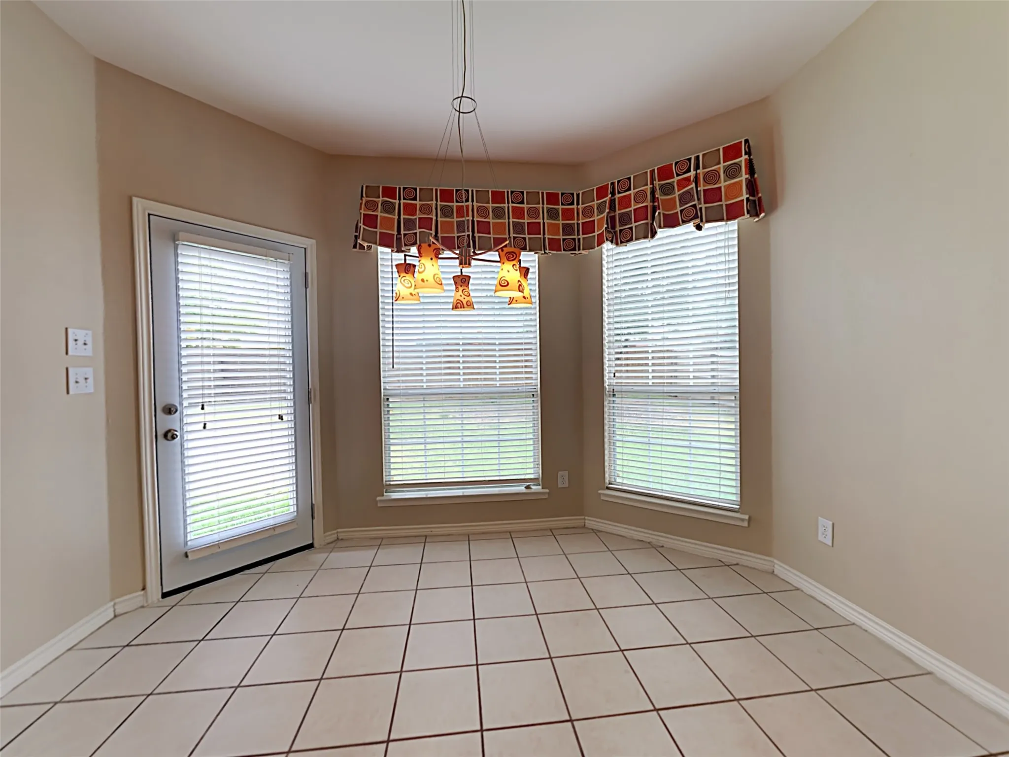 Bay window with multiple windows, glass-paneled door, tile flooring, and overhead pendant lighting