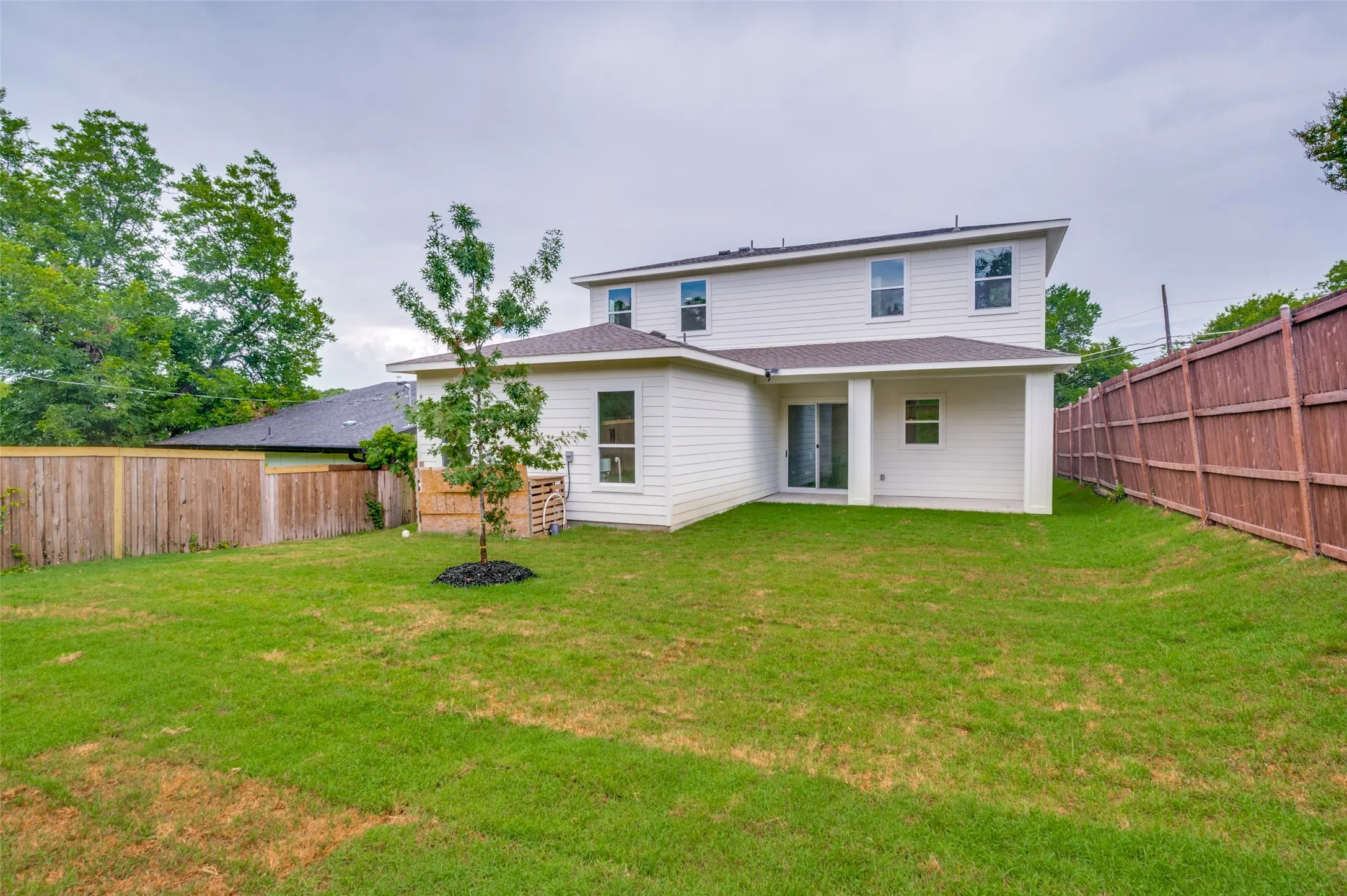 Expansive grassy yard with wood fencing, a covered patio, and white siding