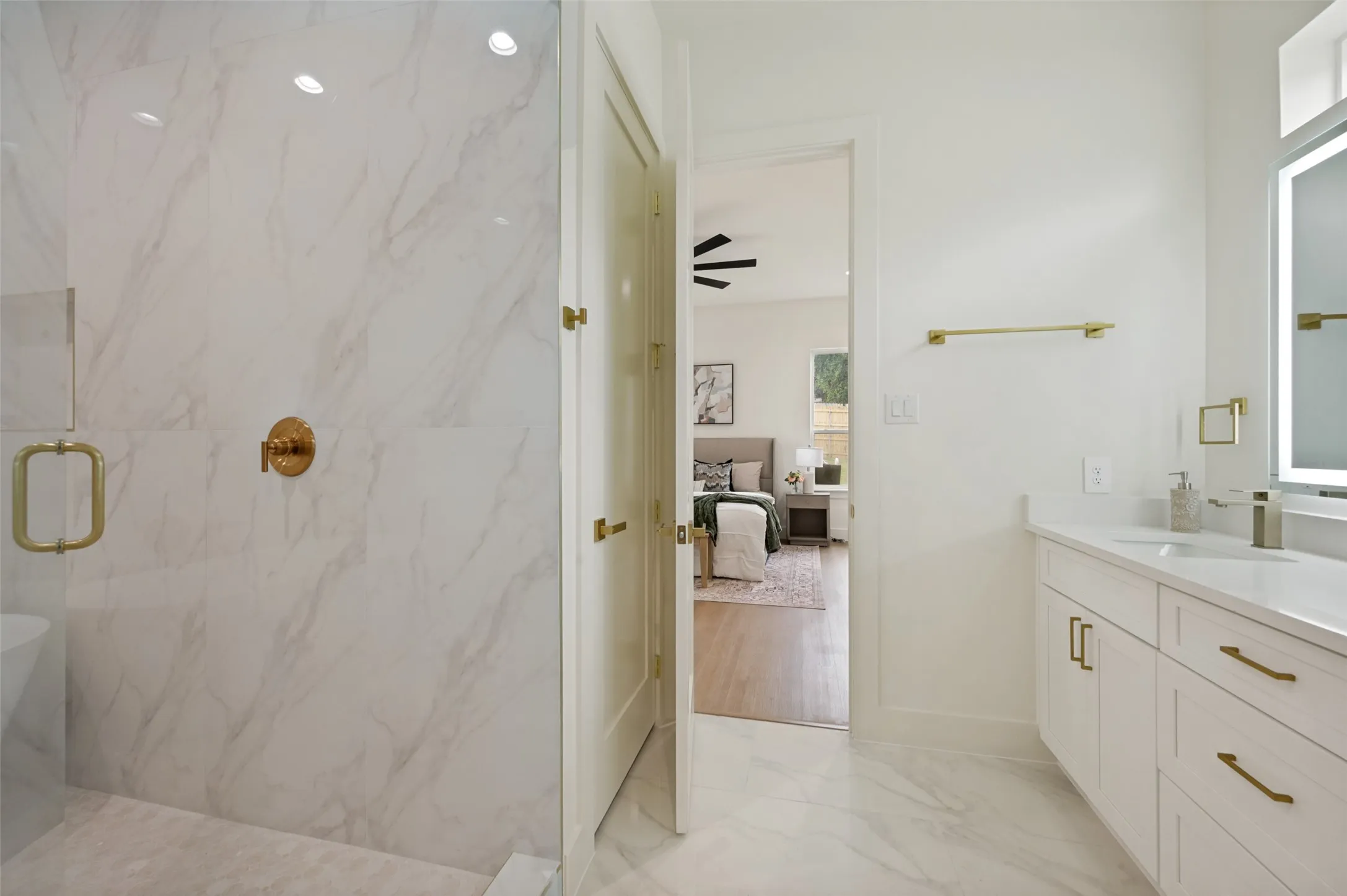 White vanity with gold-tone hardware, rectangular undermount sink, and integrated mirror lighting