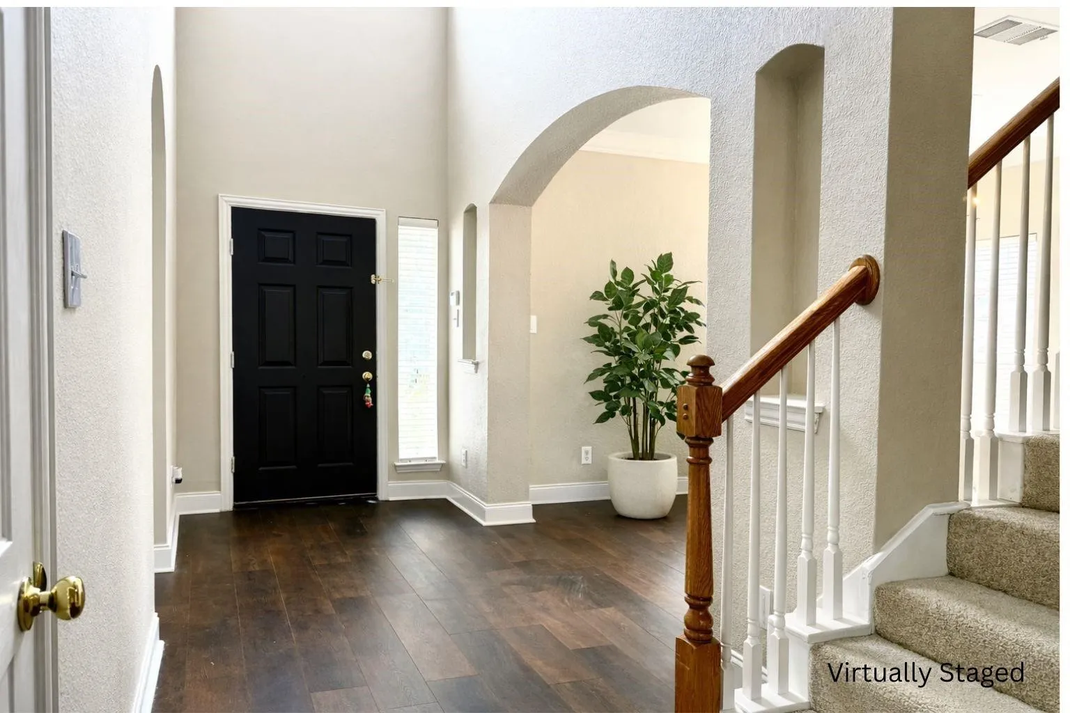 Entryway with high ceilings, dark wood-finish flooring, a paneled front door, and an arched doorway