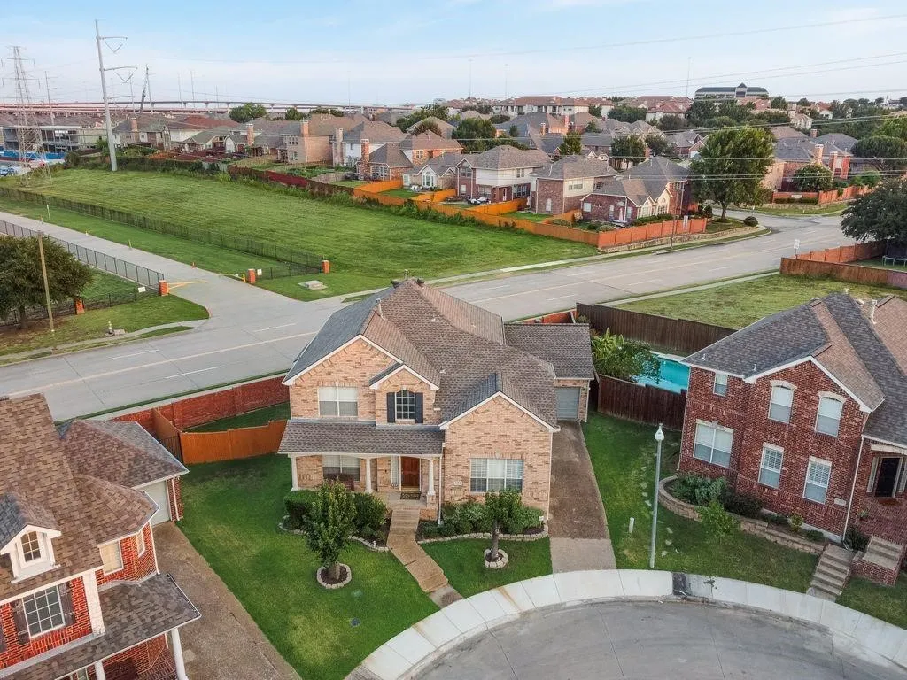Brick exterior, covered front porch, attached garage, concrete driveway, and mature landscaping