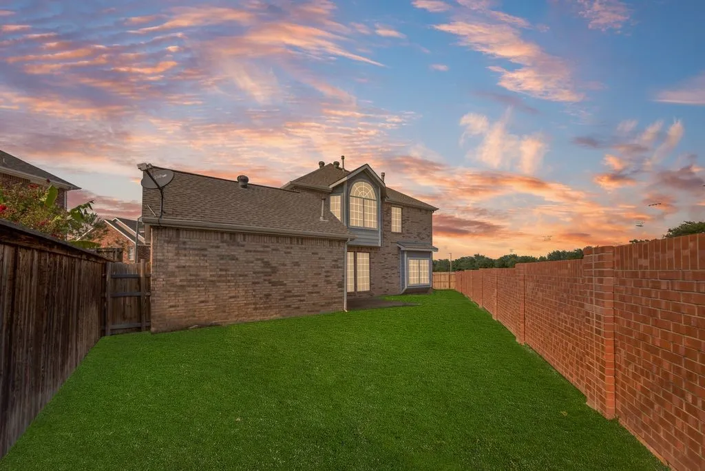 Expansive lawn bordered by a brick privacy wall and wood fence