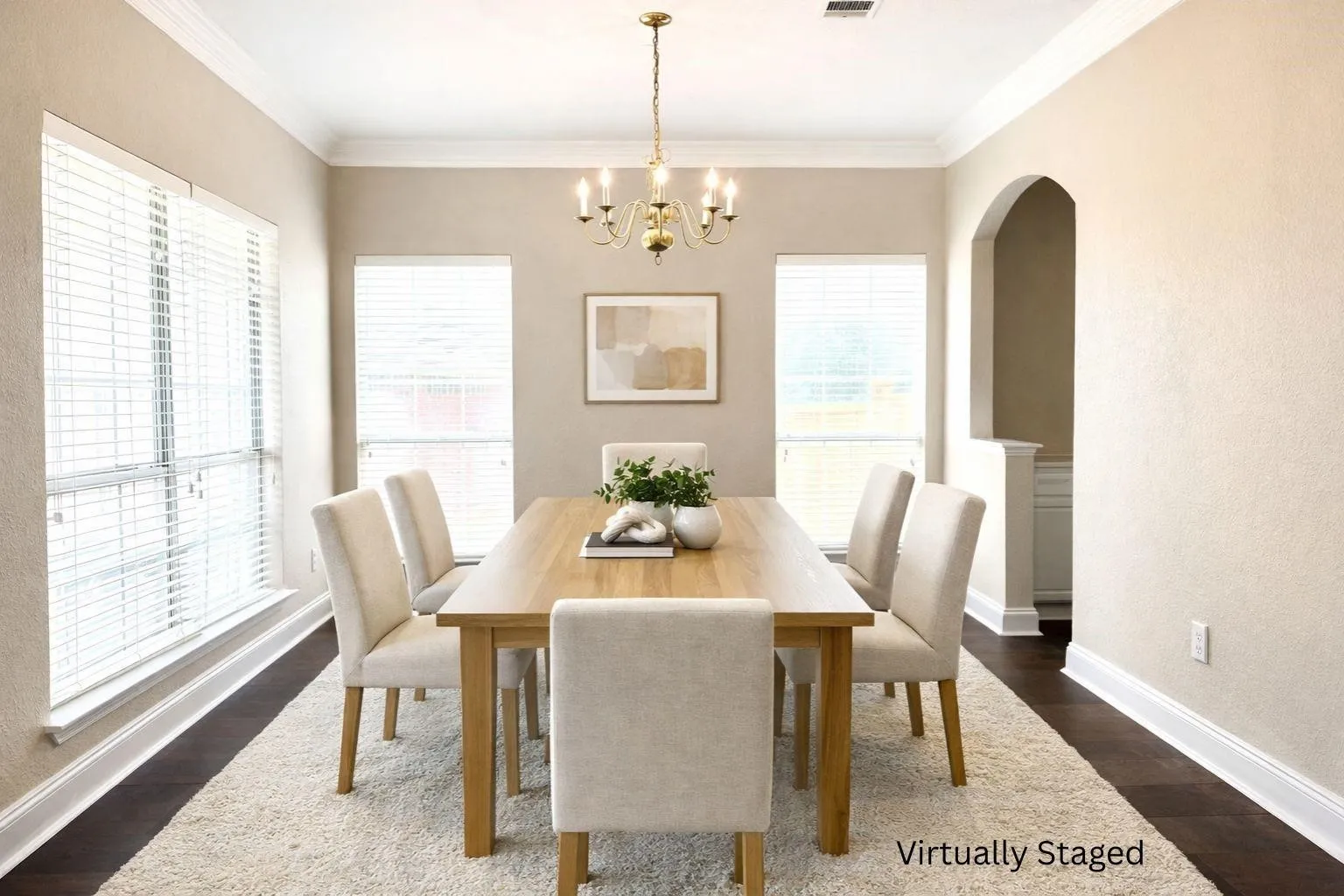 Spacious room featuring dark wood-finish flooring, multiple windows with blinds, a multi-bulb chandelier, and an arched entry
