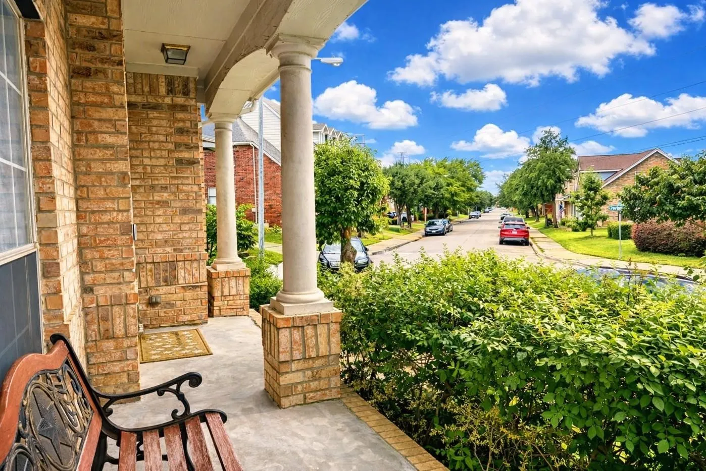 Brick exterior with a covered porch, round columns, and an integrated ceiling light fixture