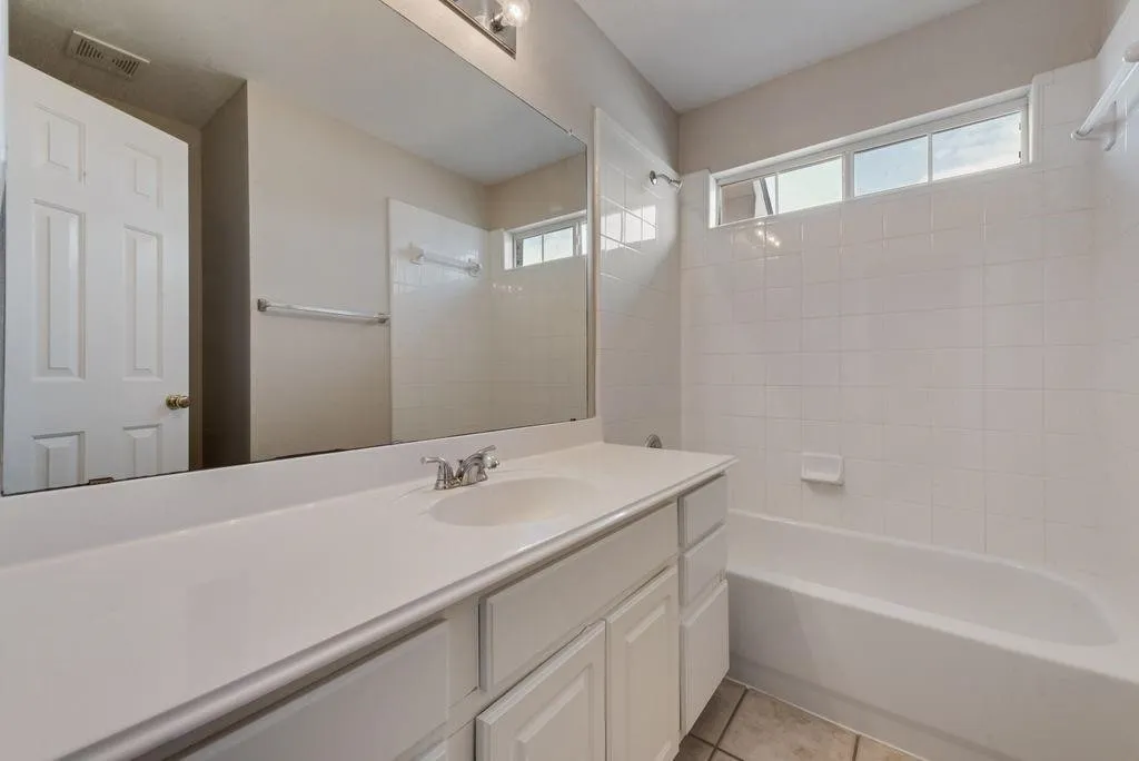 White vanity with an integrated sink, polished chrome faucet, and a large wall-mounted mirror