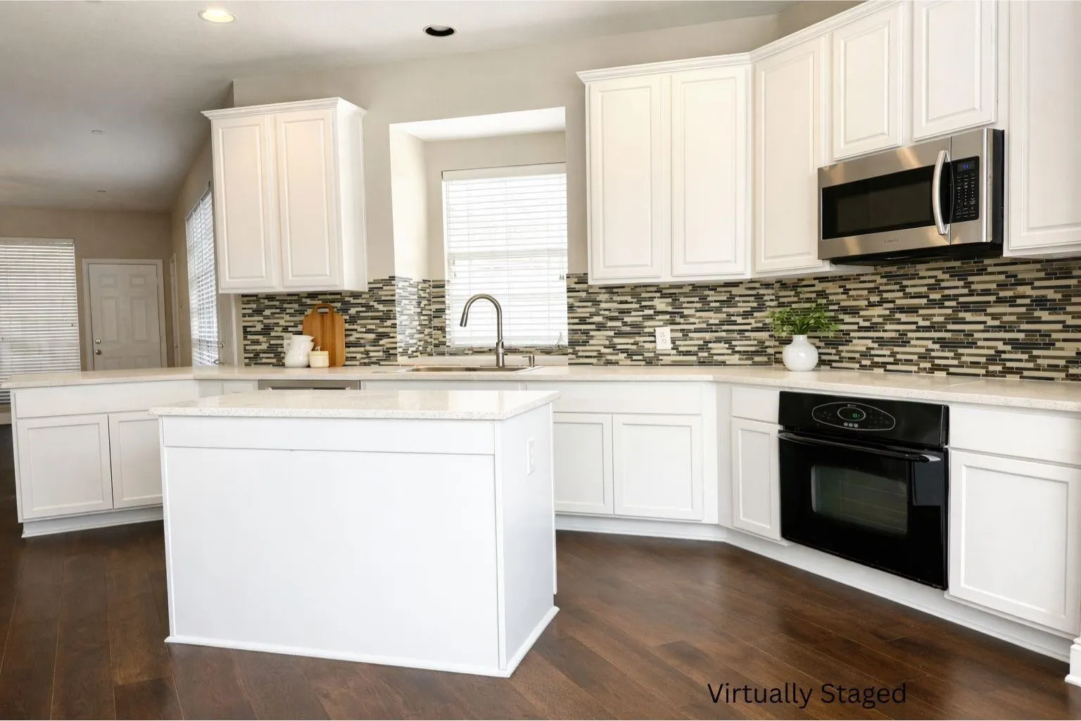 White cabinetry, dark wood-finish flooring, white countertops, built-in stainless steel microwave, and a black built-in oven
