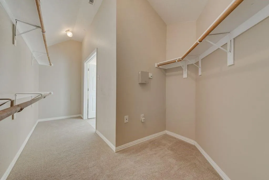Expansive walk-in closet with neutral carpeting and multiple shelving units