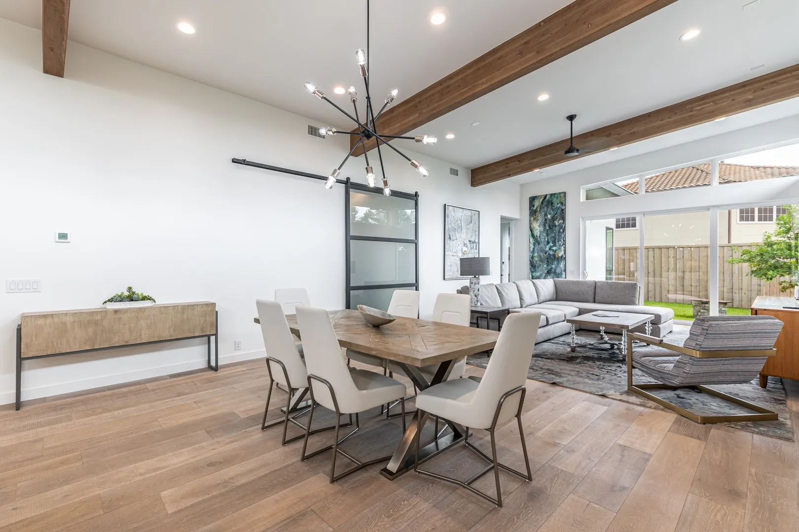 Dining room with beam ceiling, light wood finished floors, a chandelier, and recessed lighting