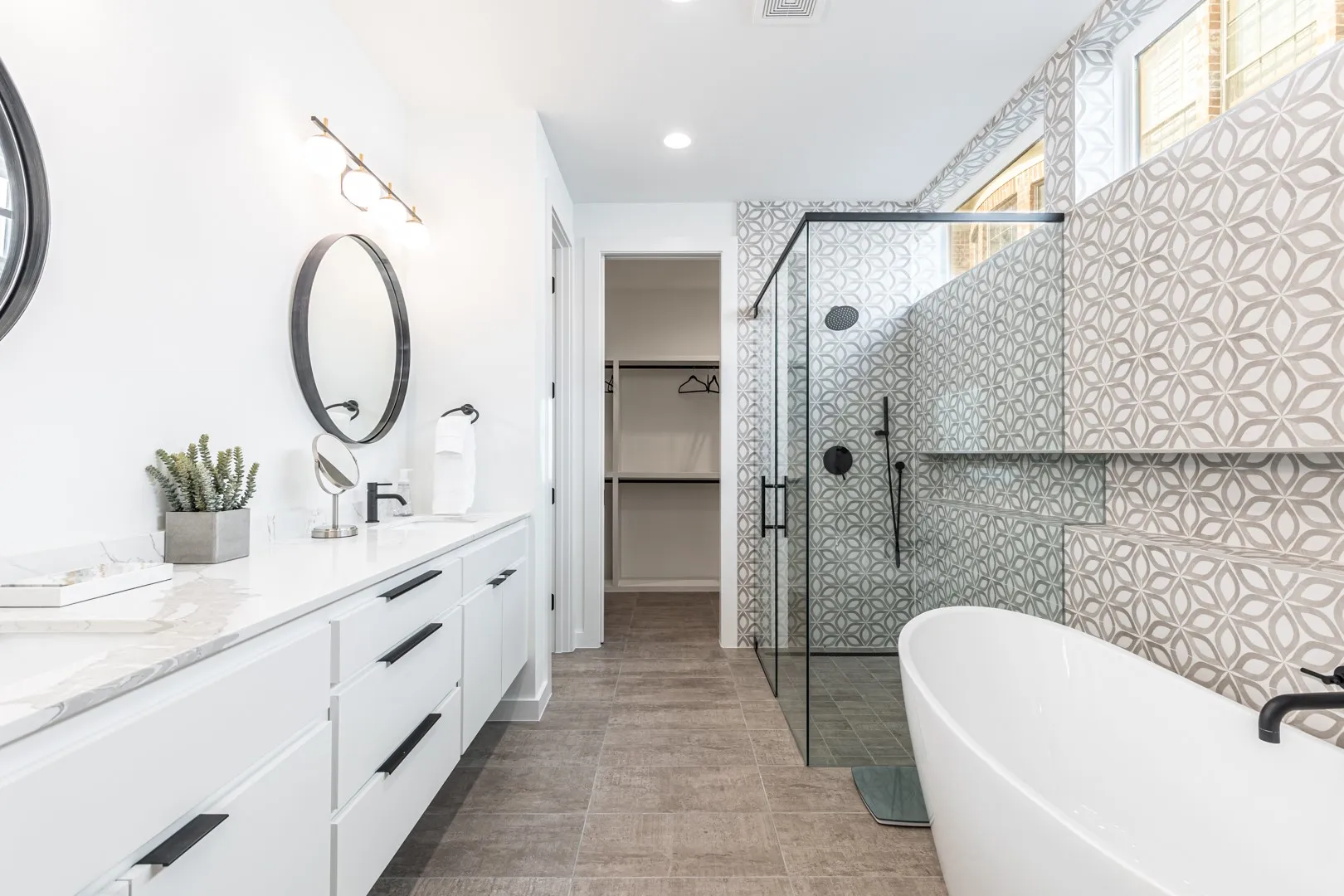 Bathroom featuring double vanity, a freestanding bath, a shower stall, a spacious closet, and recessed lighting