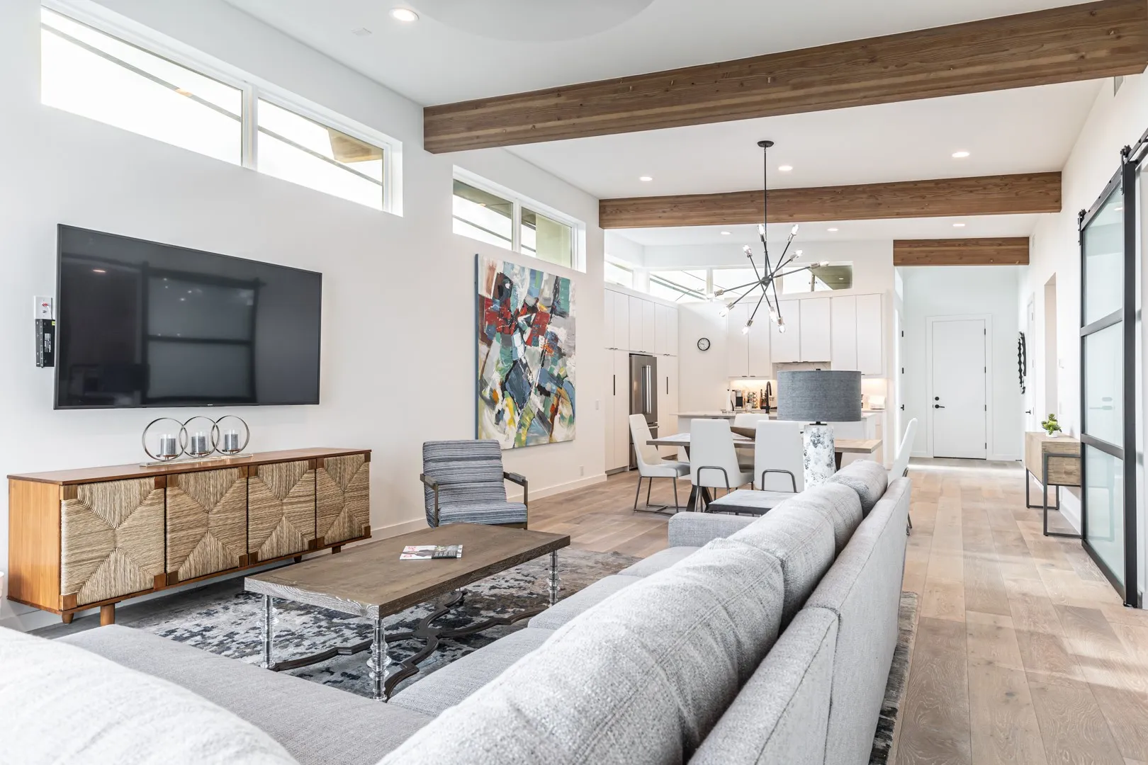Living area with beamed ceiling, light wood finished floors, recessed lighting, a chandelier, and a high ceiling