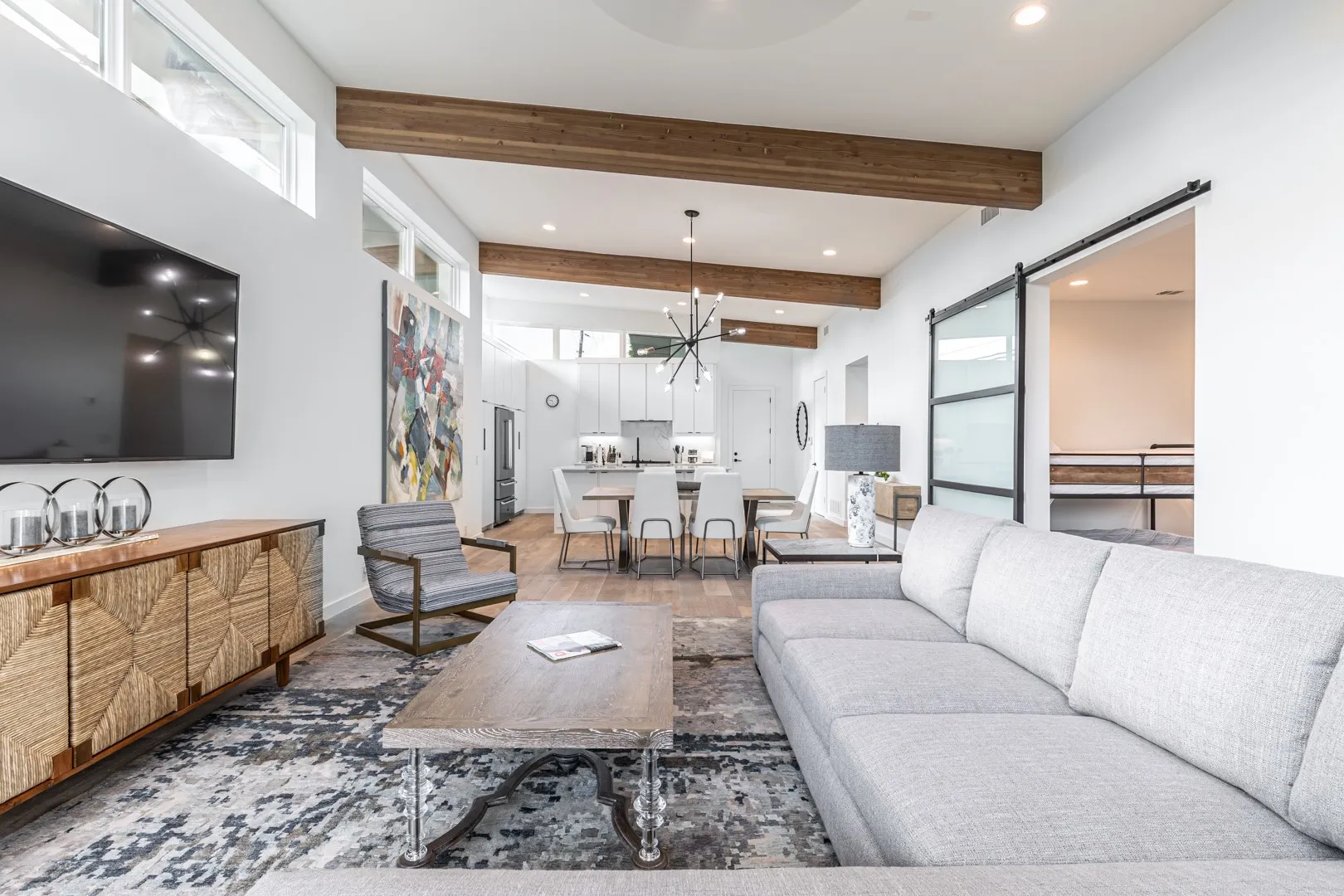 Living area featuring a barn door, beam ceiling, recessed lighting, and wood finished floors