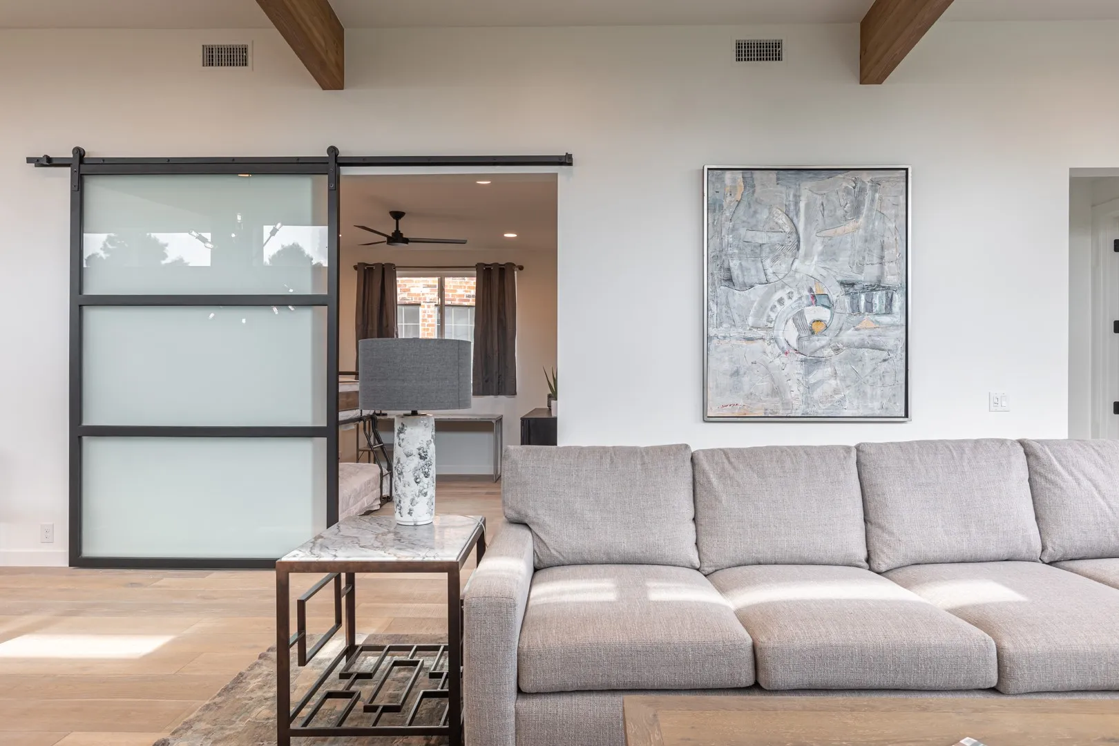 Living area featuring beamed ceiling, wood finished floors, and a ceiling fan