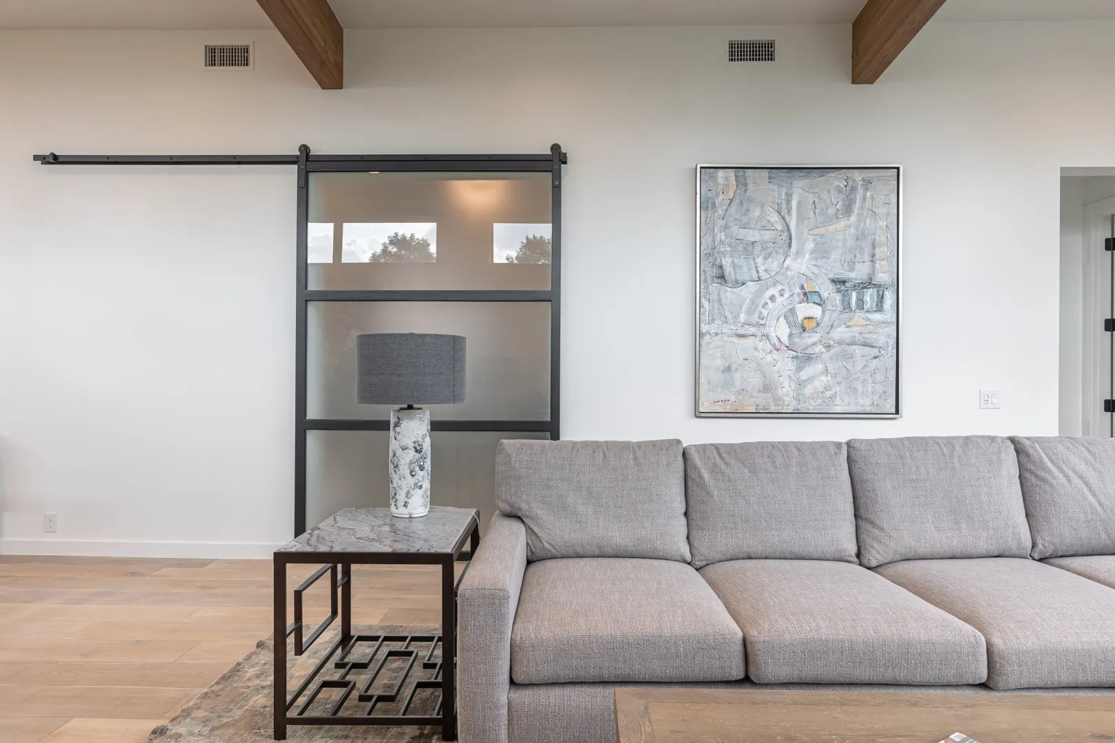 Living room with beamed ceiling, wood finished floors, and a barn door