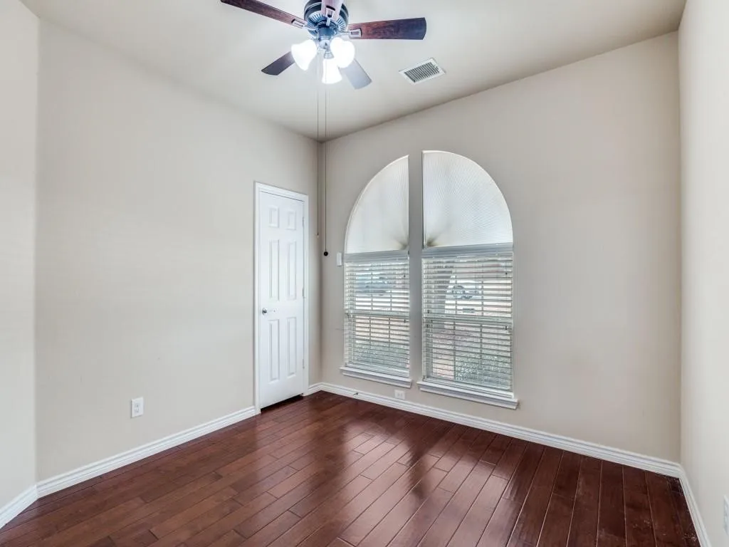 Wood-finish flooring, arched window with blinds, ceiling fan, and paneled door