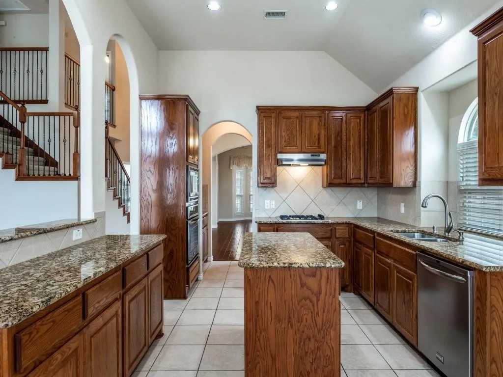 Kitchen featuring wood cabinetry, granite countertops, stainless steel appliances, and a central island