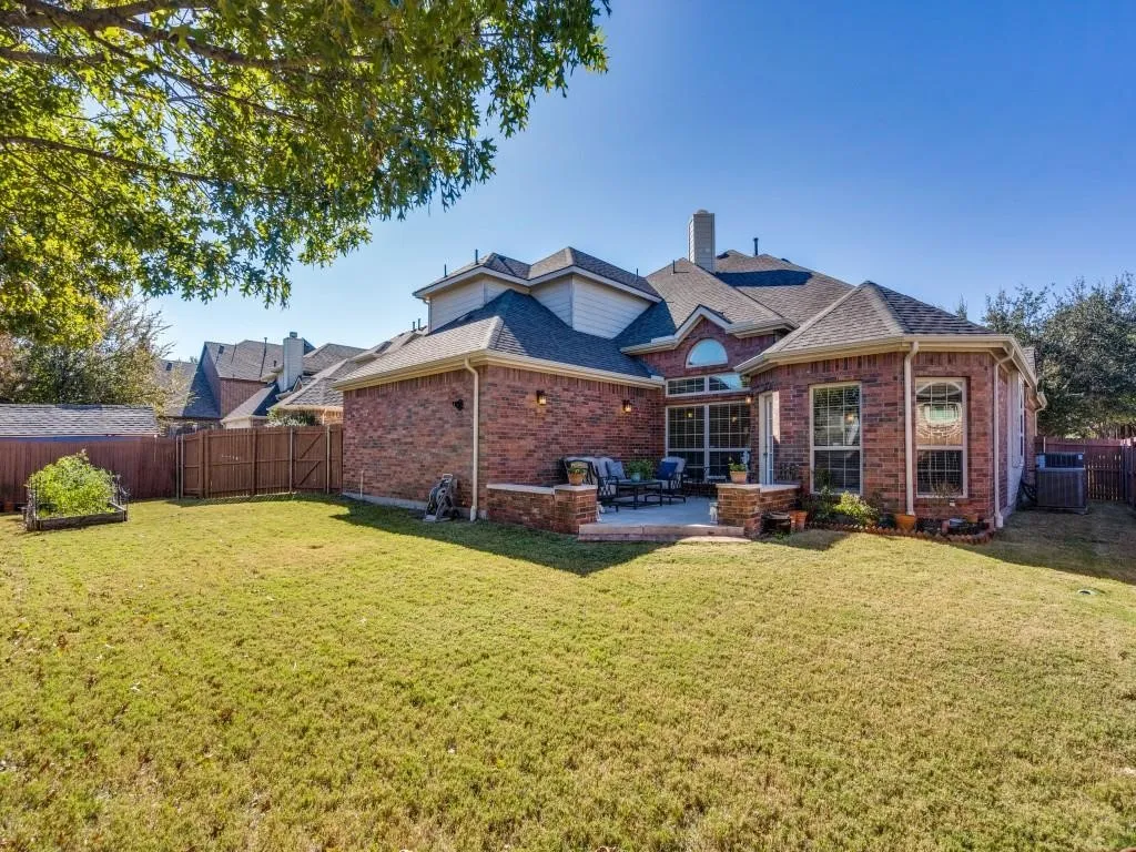 Brick exterior with multiple gables, a ground-level patio, and an expansive lawn