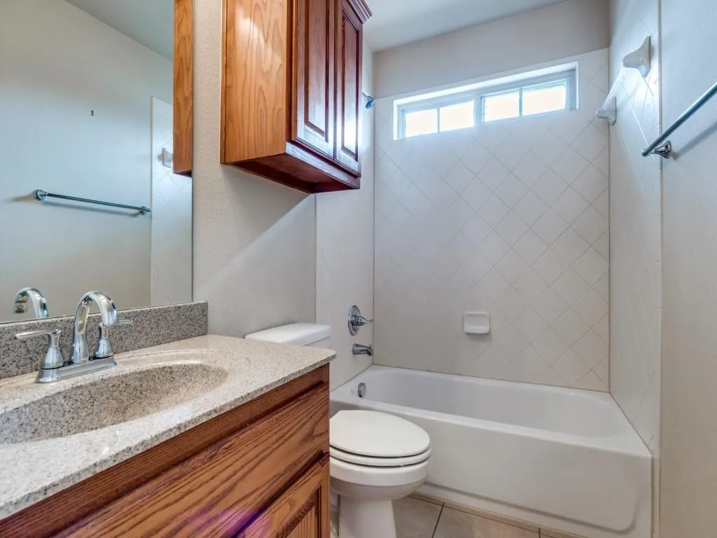 Granite-look countertop with an undermount sink, wood-finish vanity, and integrated mirror