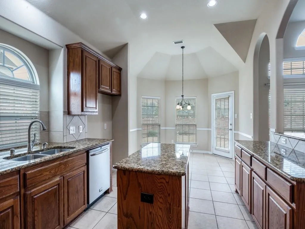 Kitchen featuring wood cabinetry, granite countertops, an undermount double basin sink, and a tiled​​‌​​​​‌​​‌‌​‌‌​​​‌‌​‌​‌​‌​​​‌​​ backsplash
