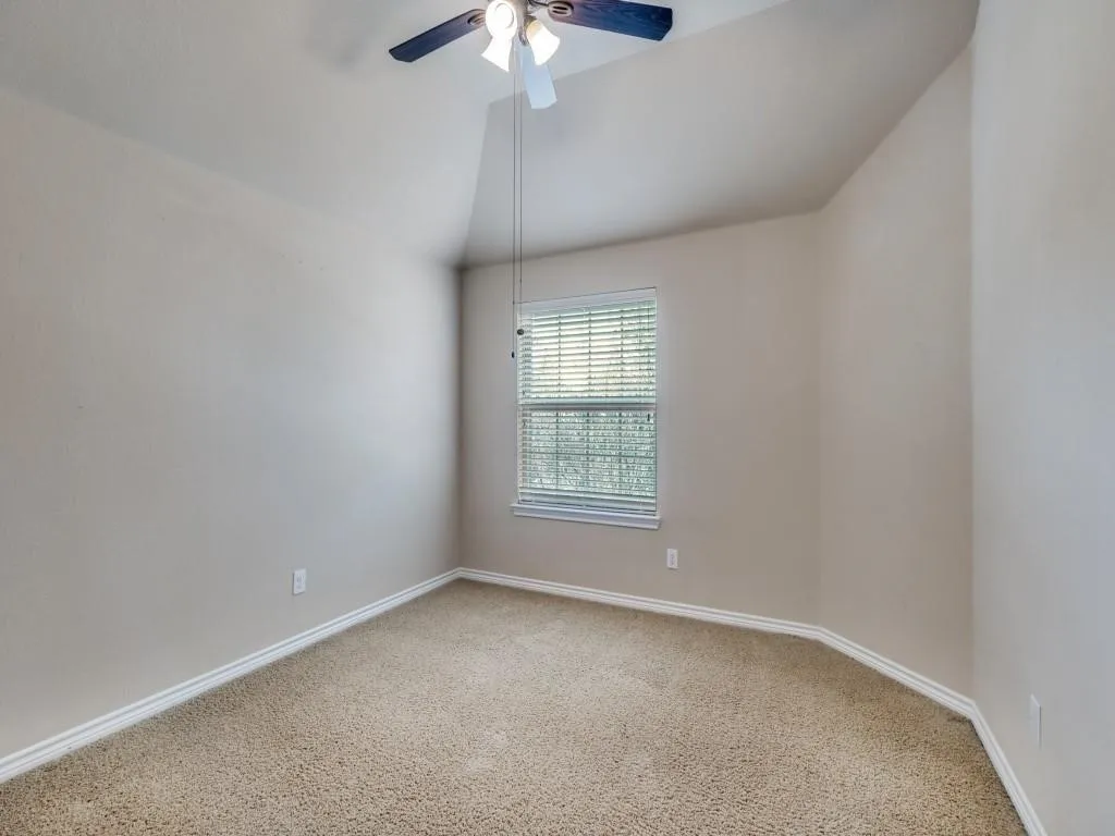 Recessed window with blinds, ceiling fan with integrated lighting, textured carpeting, and neutral wall tones
