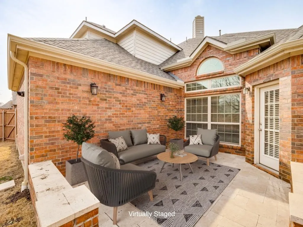 Brick exterior with a stone patio, multiple windows, and exterior lighting fixtures