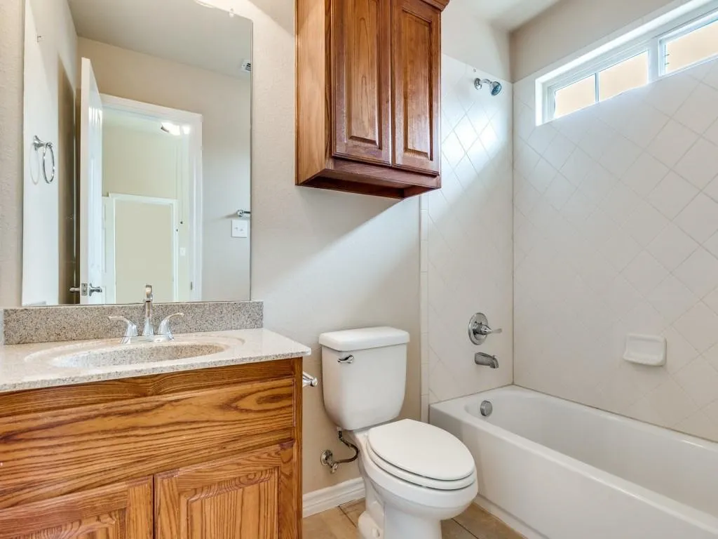 Wood-finish vanity with a light-toned countertop, undermount sink, and chrome faucet