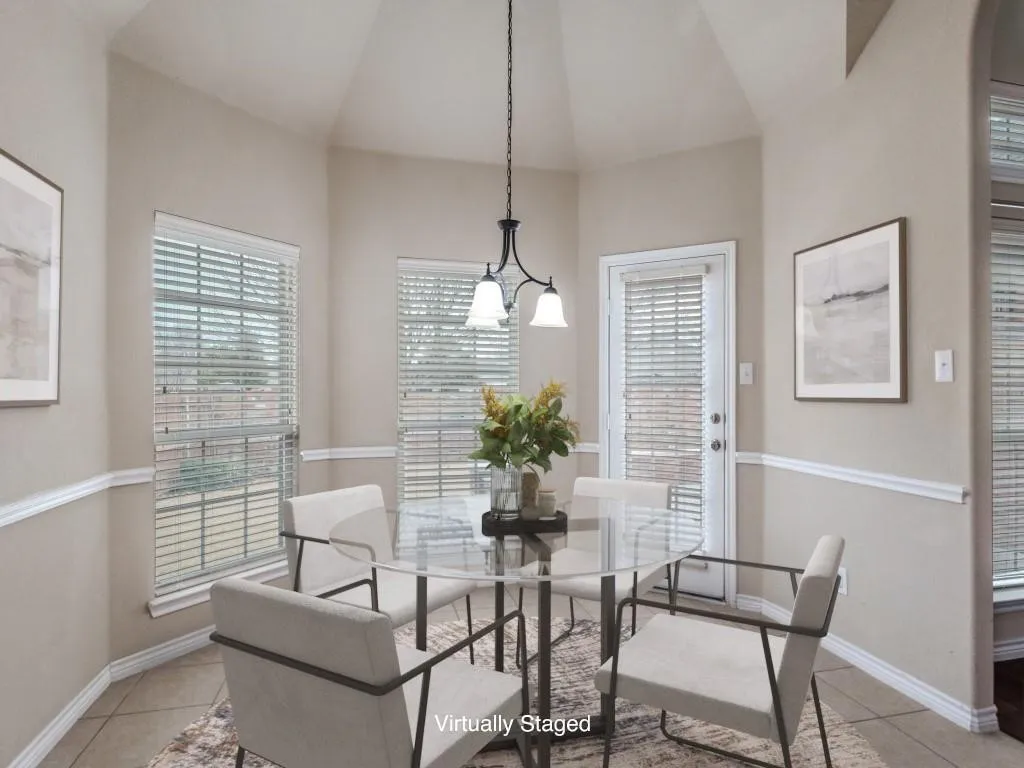 Vaulted ceiling, multiple windows with blinds, built-in overhead lighting, white trim molding, and tiled flooring