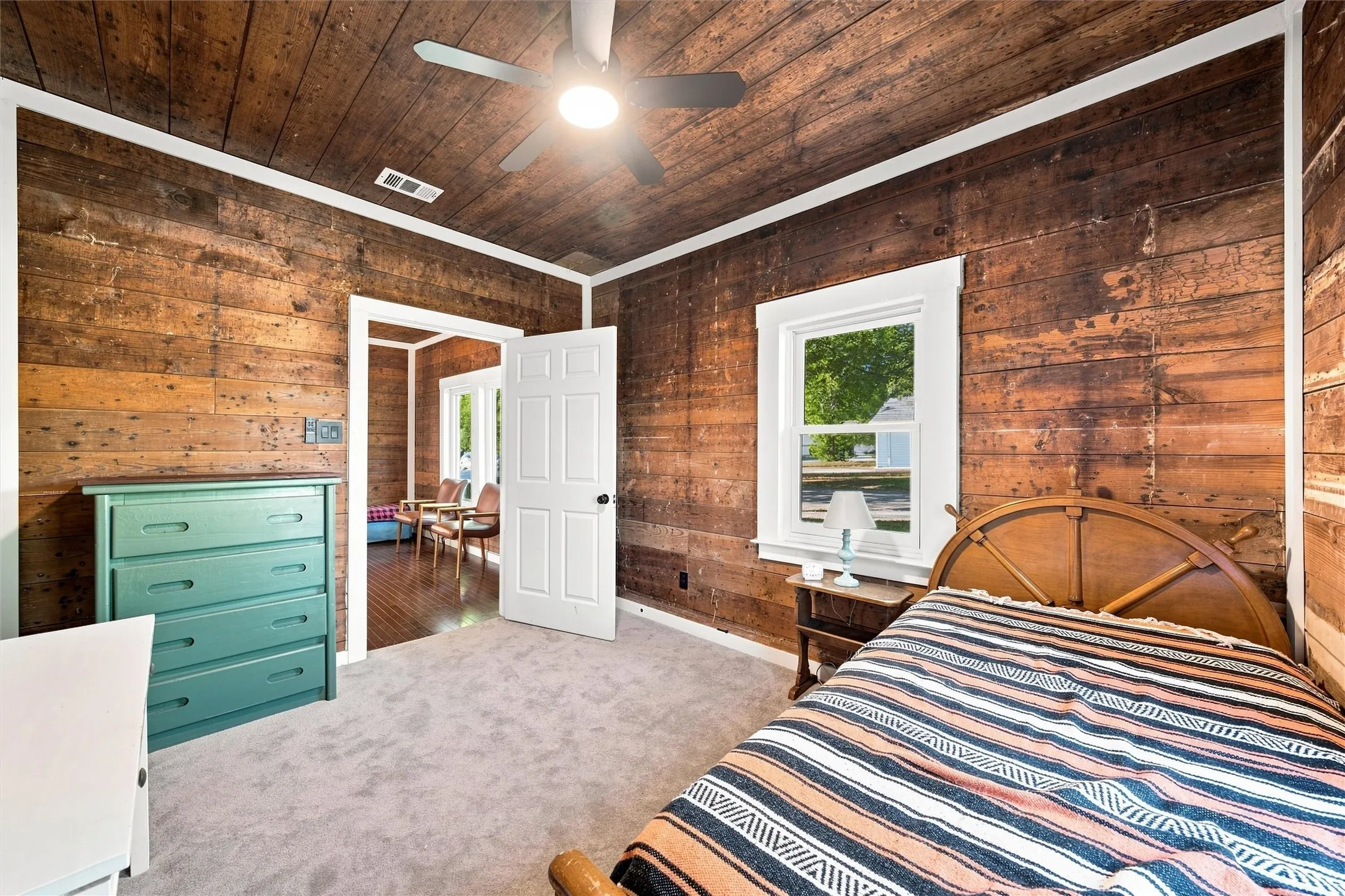 Hardwood plank walls and ceiling, wall-to-wall carpeting, white trim, and a ceiling fan with integrated lighting