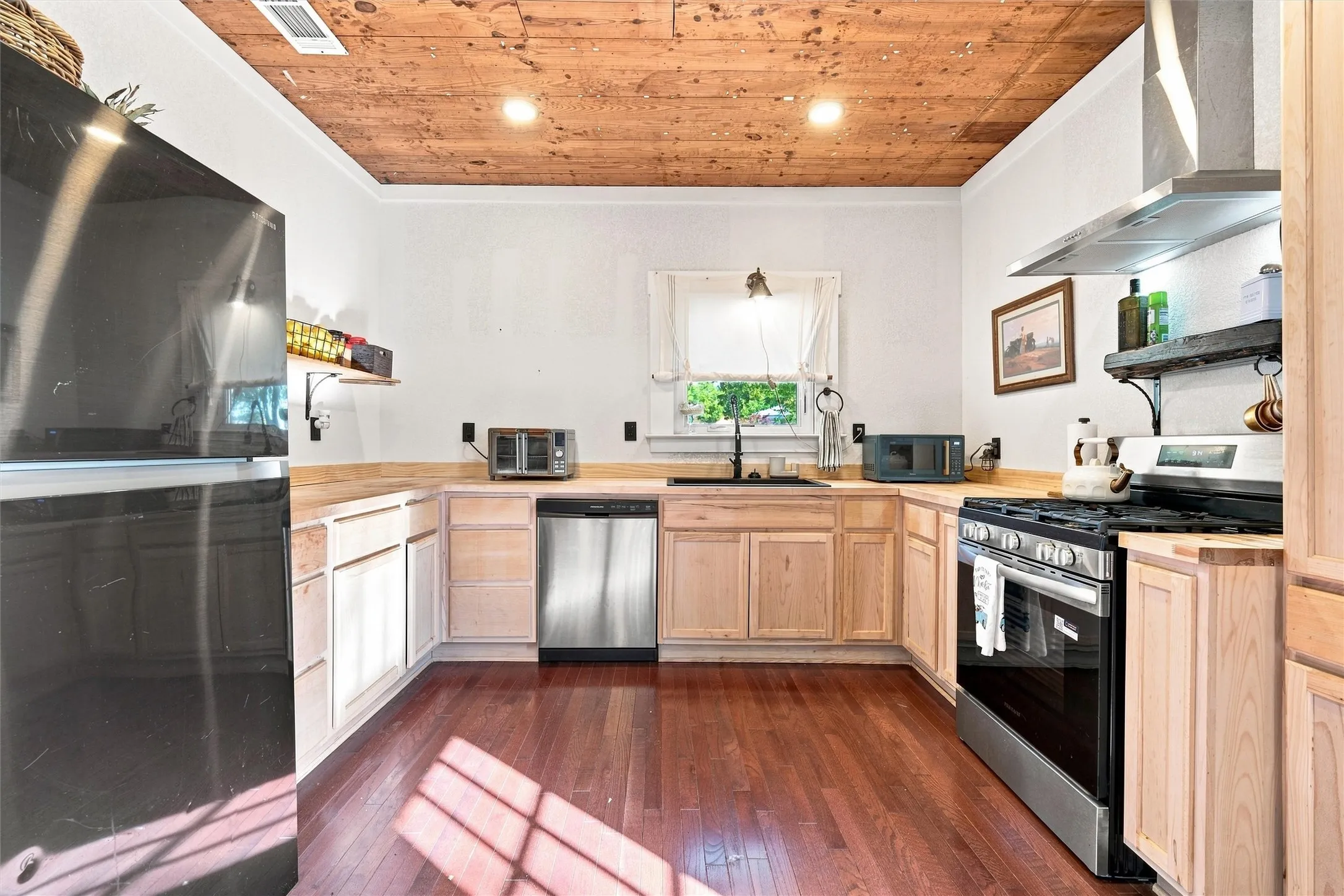 Kitchen featuring wood-finish flooring, natural wood cabinetry, wood countertops, stainless steel appliances, and a wood-paneled ceiling