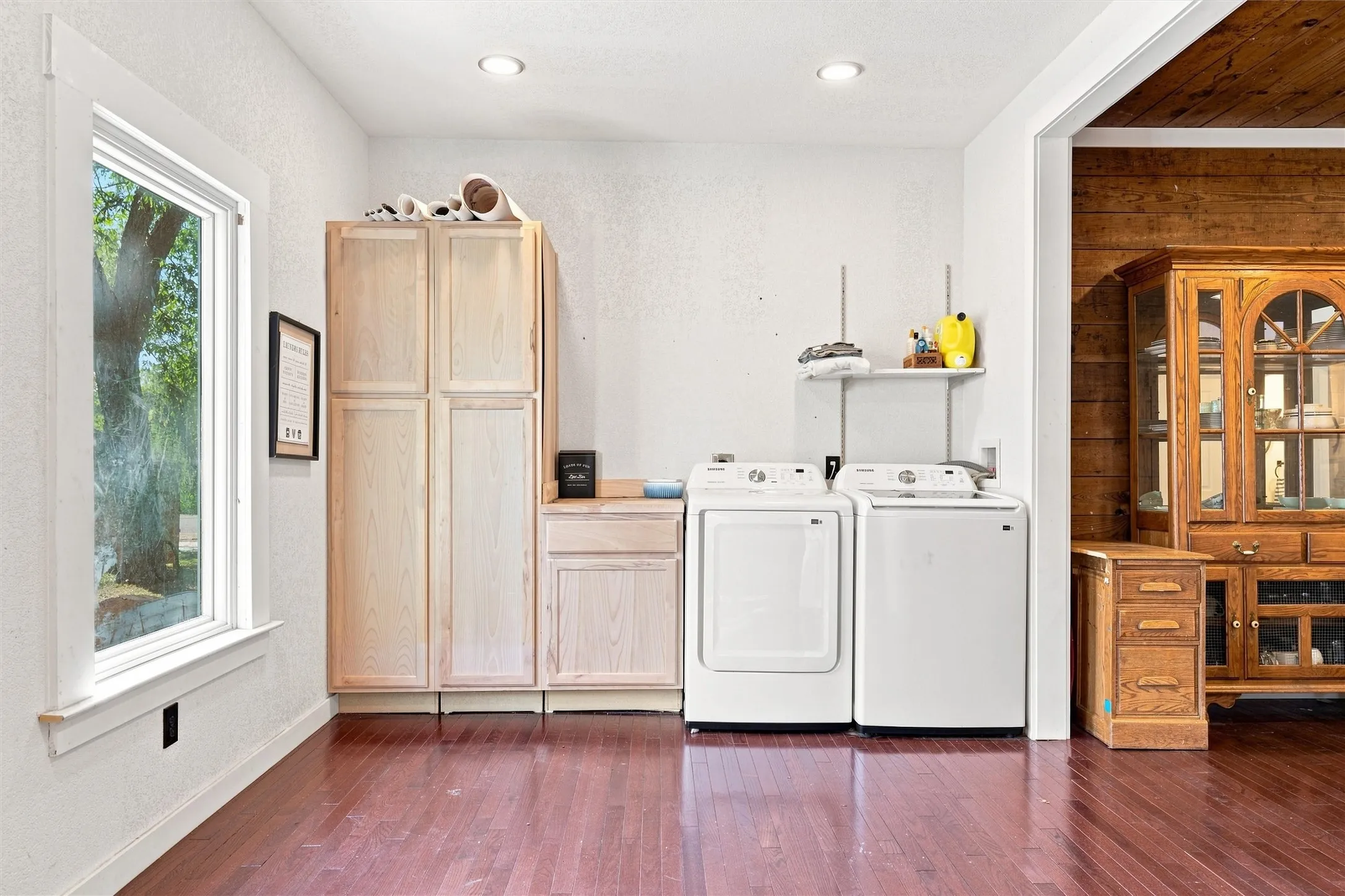 Laundry area featuring wood-finish flooring, built-in cabinetry, and a single window