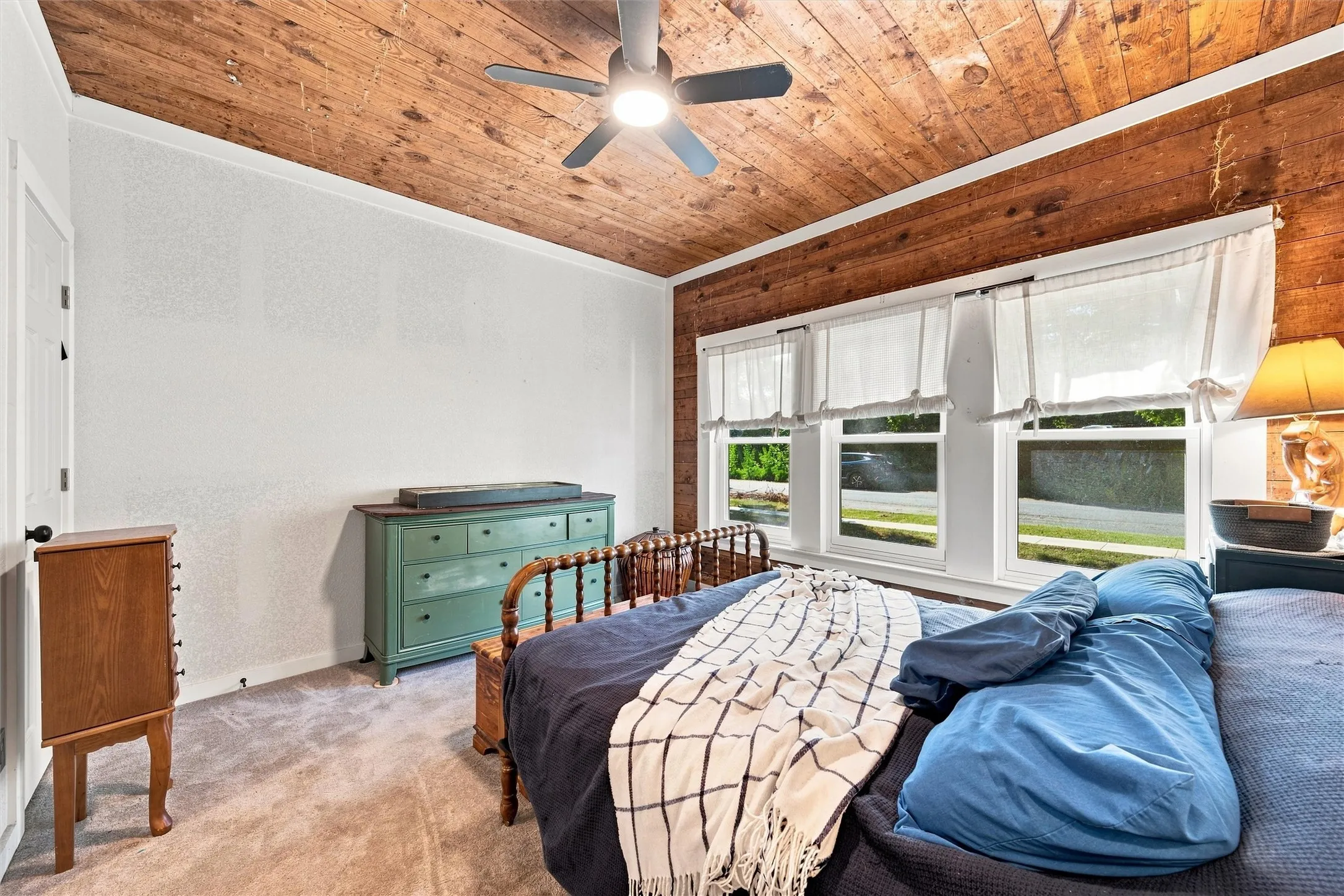 Wood-paneled ceiling with a ceiling fan, white walls, and carpet flooring