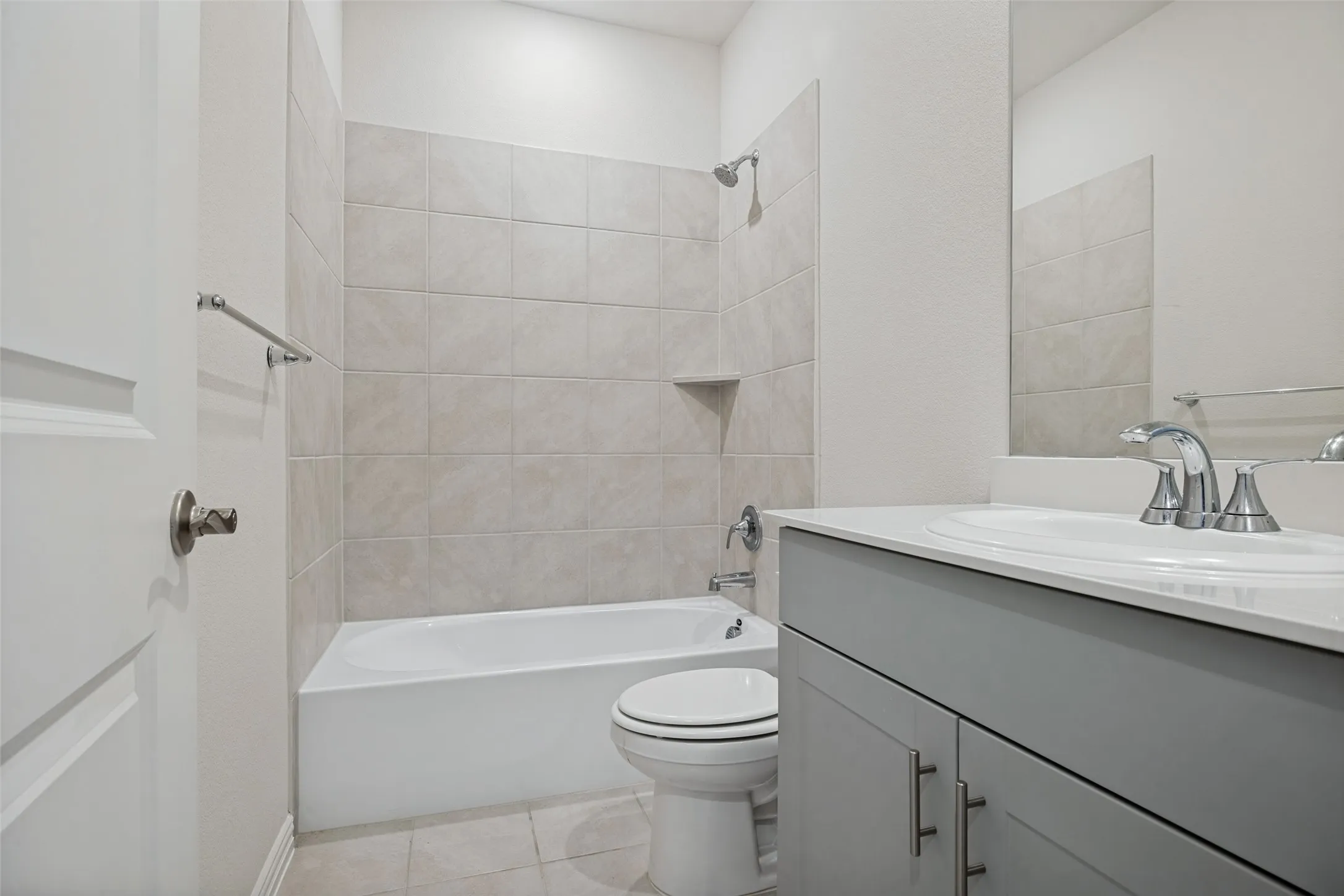 Lovely shared Bathroom featuring a single vanity with gray cabinetry, white countertop, and bathtub with shower combo
